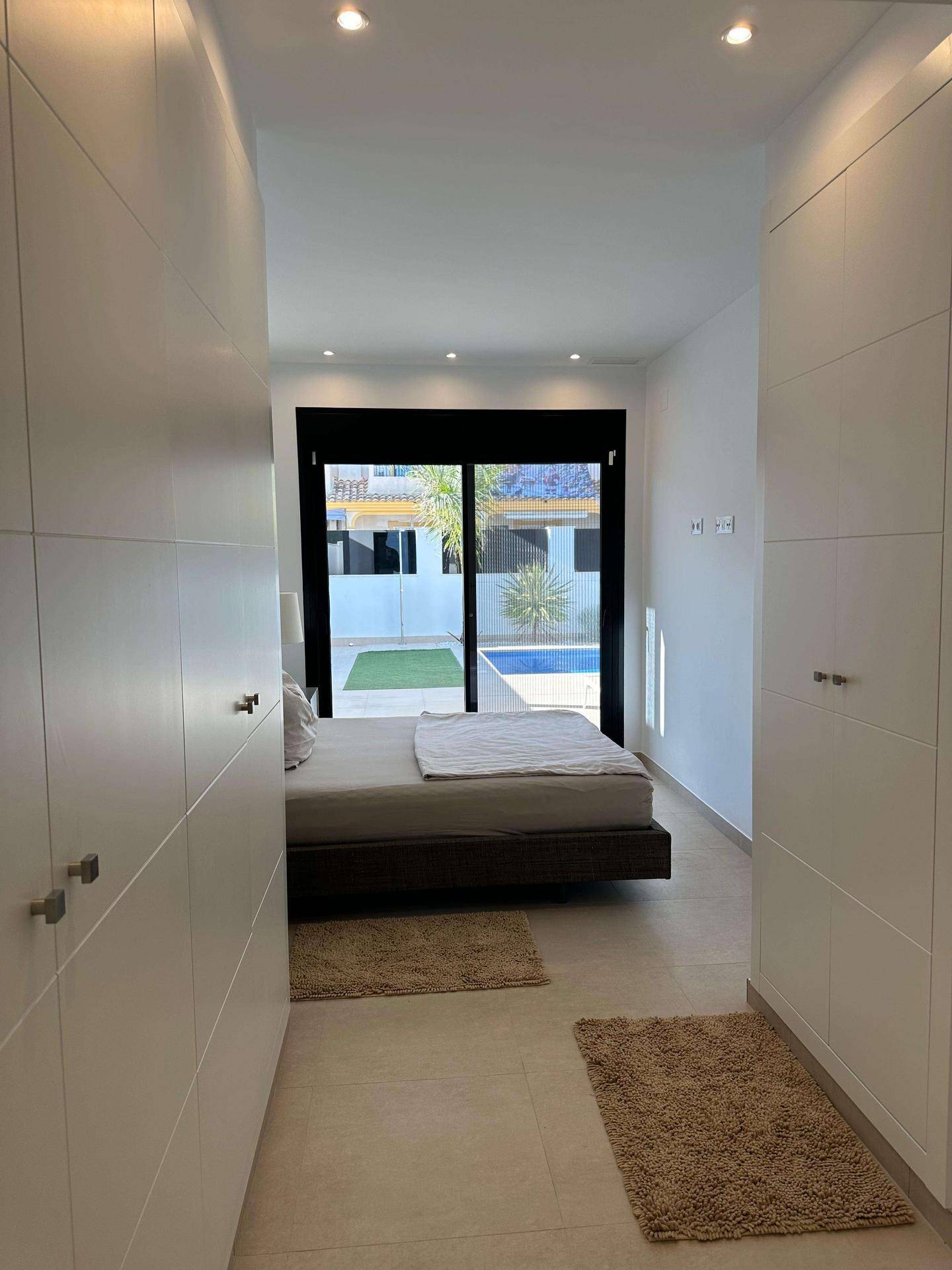 Schlafzimmer mit durchgehendem Einbauschrank und Blick auf den Außenbereich.