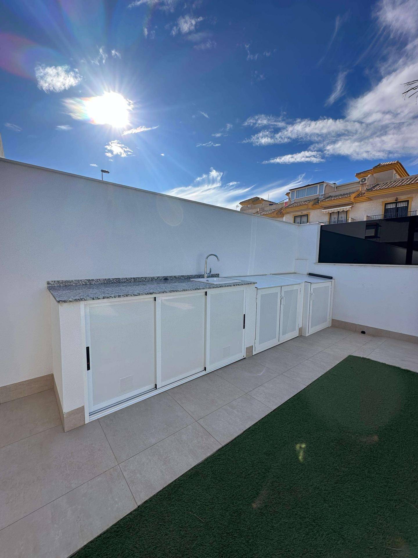 Moderne Außenküche mit Granitarbeitsplatte und Spüle im sonnigen Gartenbereich.