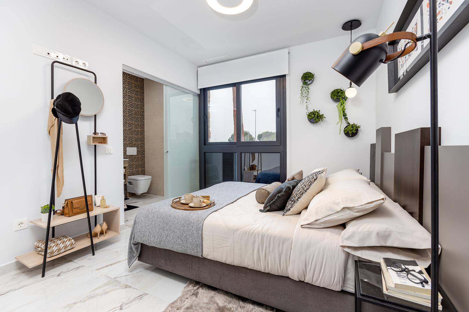 Modernes Schlafzimmer mit Doppelbett, stilvoller Einrichtung und Zugang zum Badezimmer.