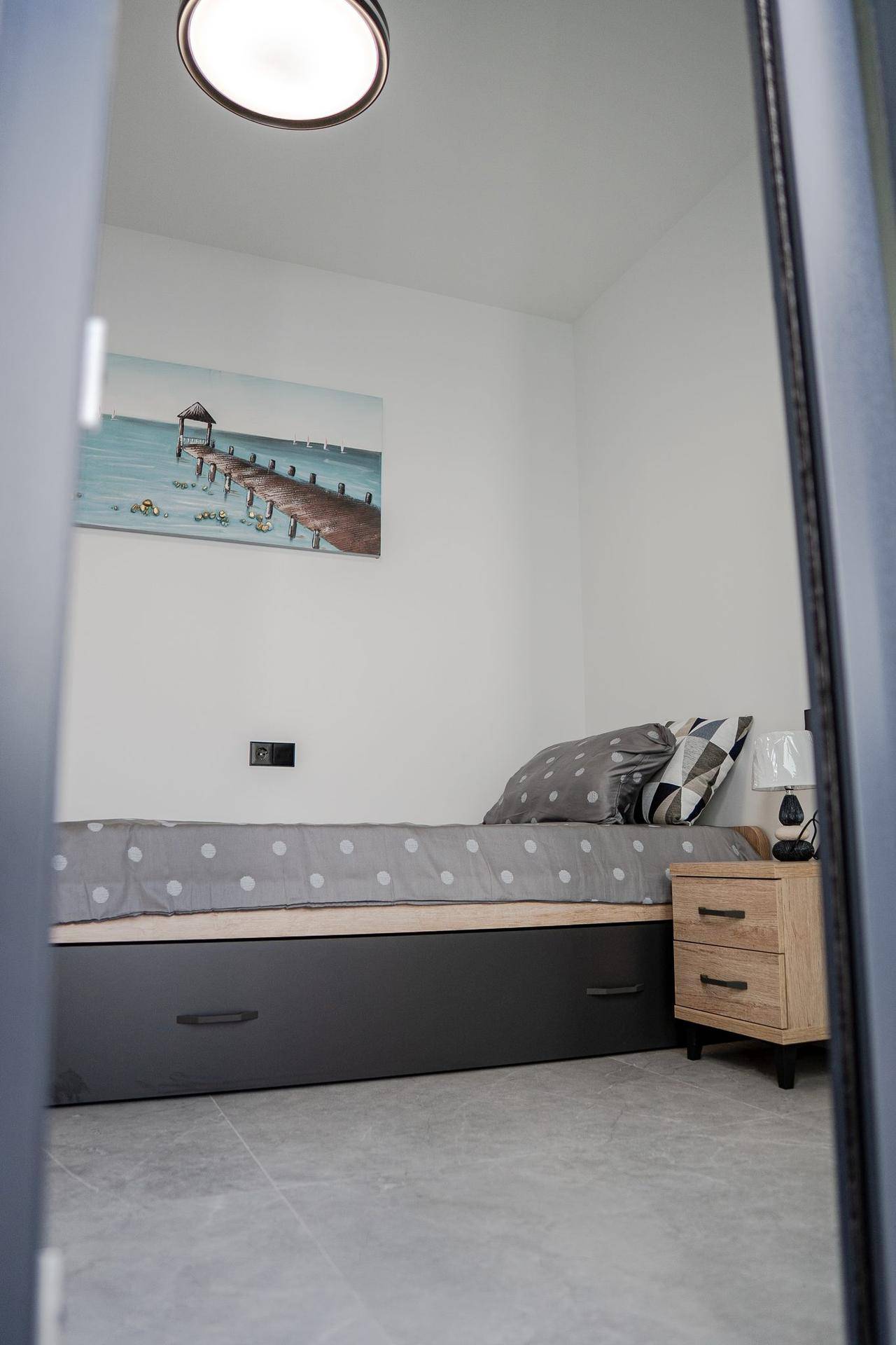 Kleines Schlafzimmer mit Einzelbett, Nachttisch und minimalistischer Einrichtung.