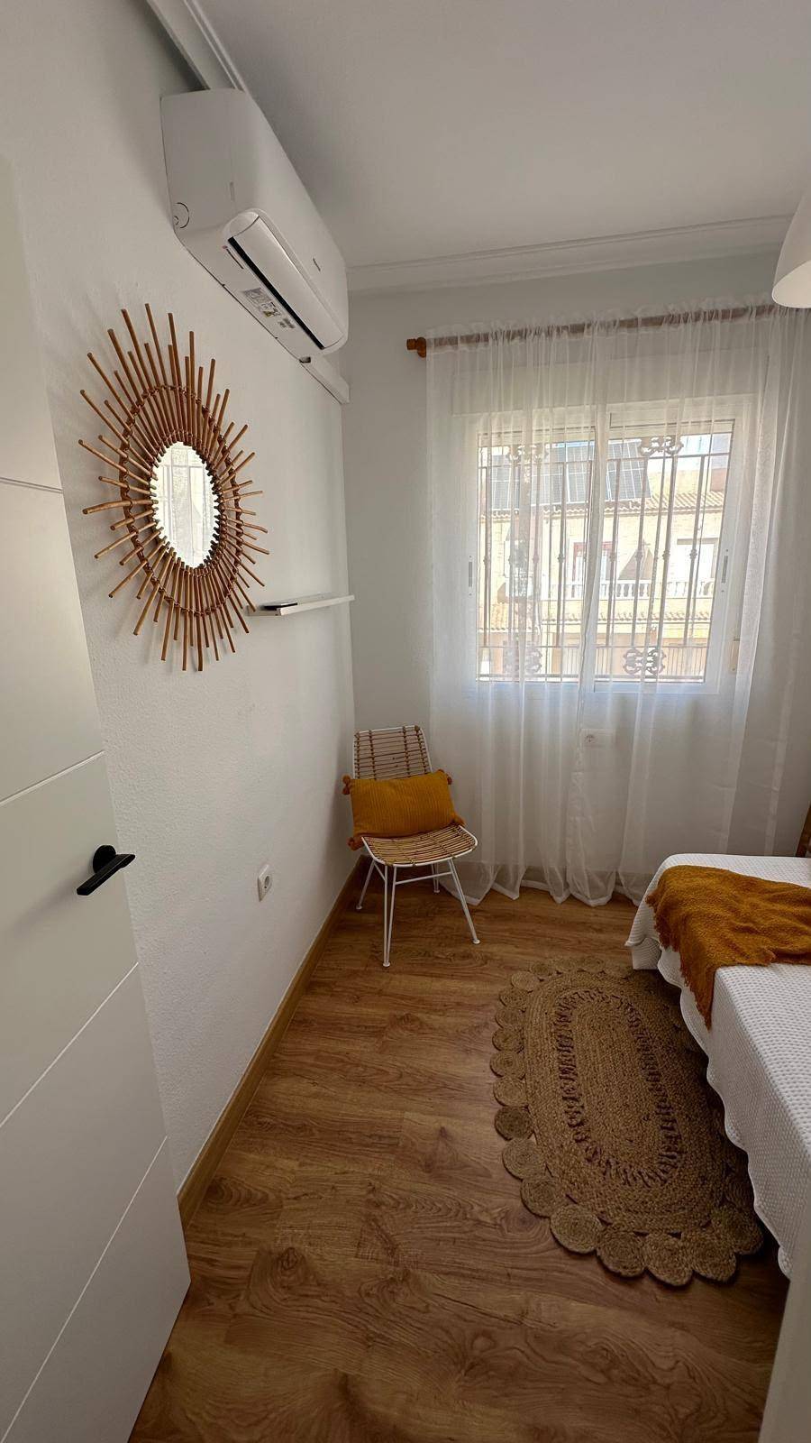 Schlafzimmer mit Einzelbett, Holzboden und Klimaanlage, dekoriert mit einem Spiegel.