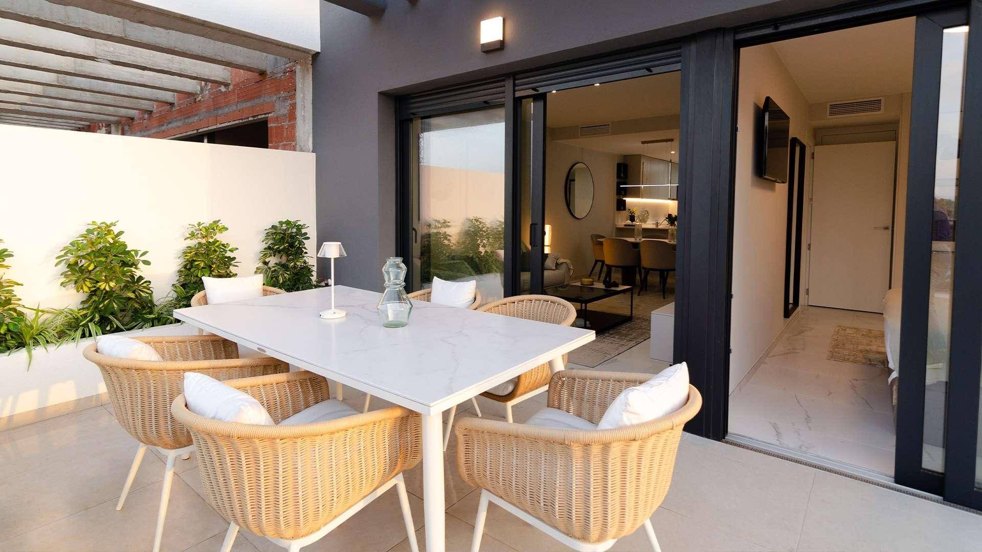 Geräumige Terrasse mit Esstisch und Blick in den modernen Wohnbereich durch große Schiebefenster.