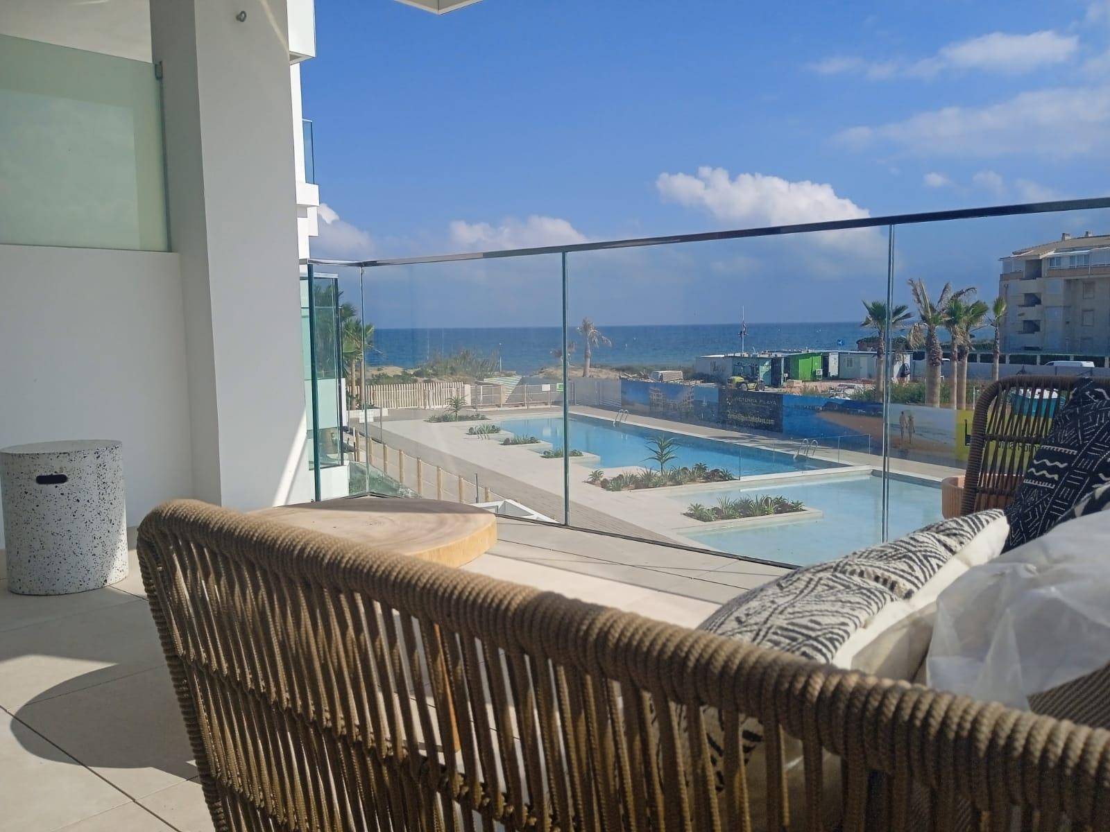 Gemütlicher Balkon mit Rattanmöbeln und weitem Blick über den Pool zum Meer.