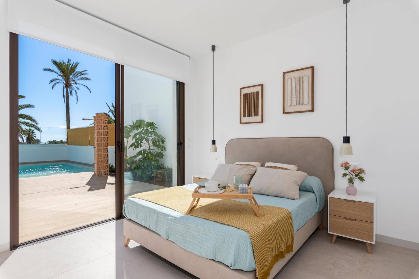 Helles Schlafzimmer mit großen Fenstern und direktem Blick auf den Poolbereich.