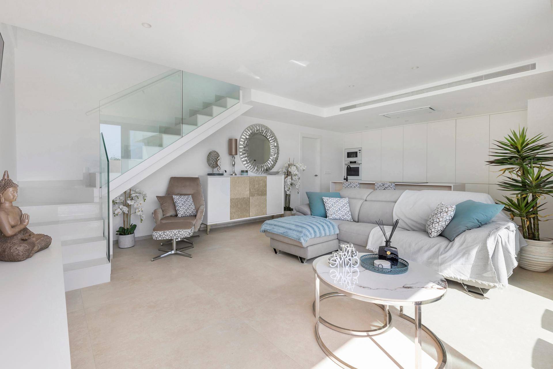 Geräumiger Wohn- und Küchenbereich mit Treppe, großem Sofa und moderner Einrichtung.