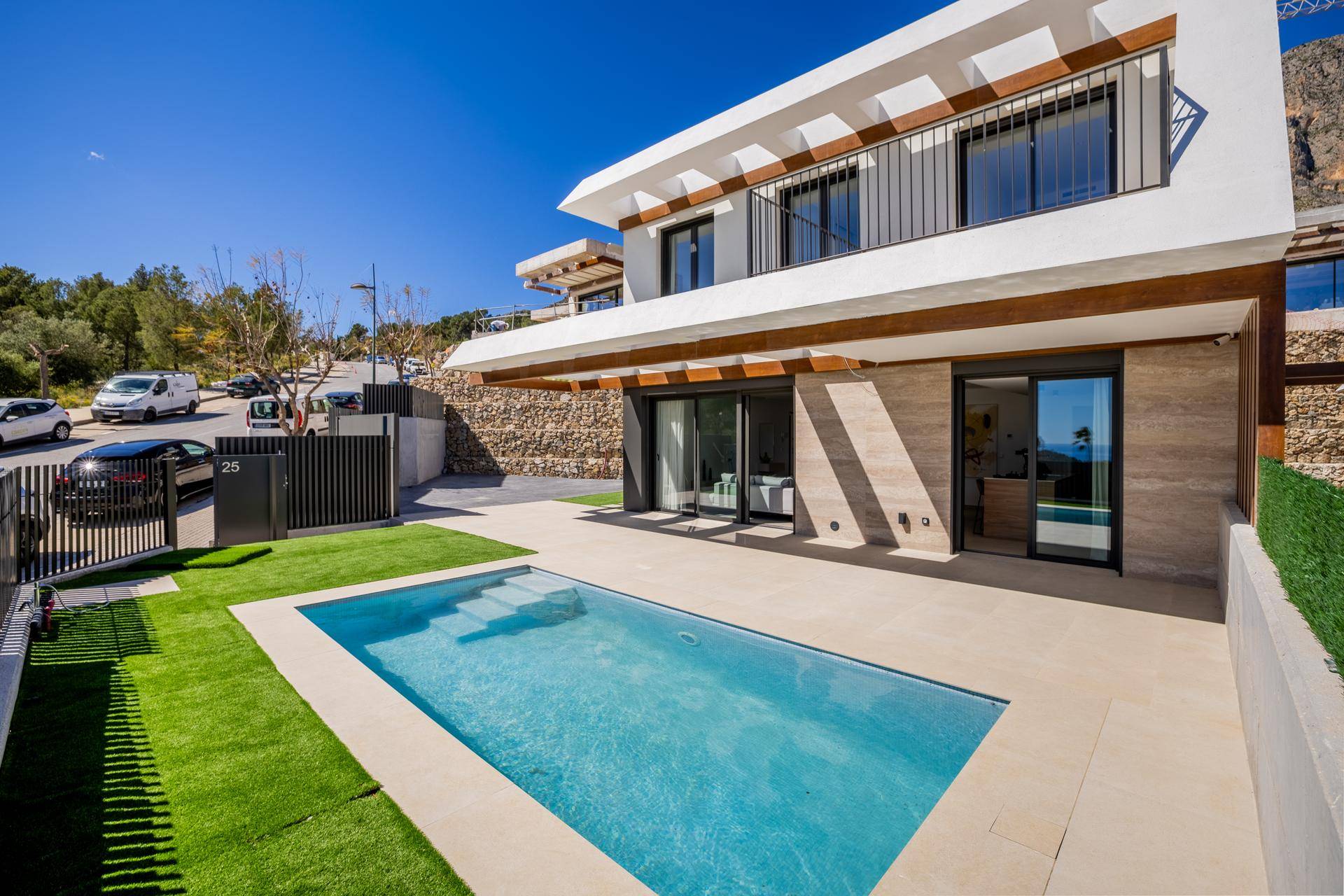 Moderne Villa mit Poolbereich und Kunstrasen, angrenzend an eine ruhige Wohnstraße mit Parkplätzen.