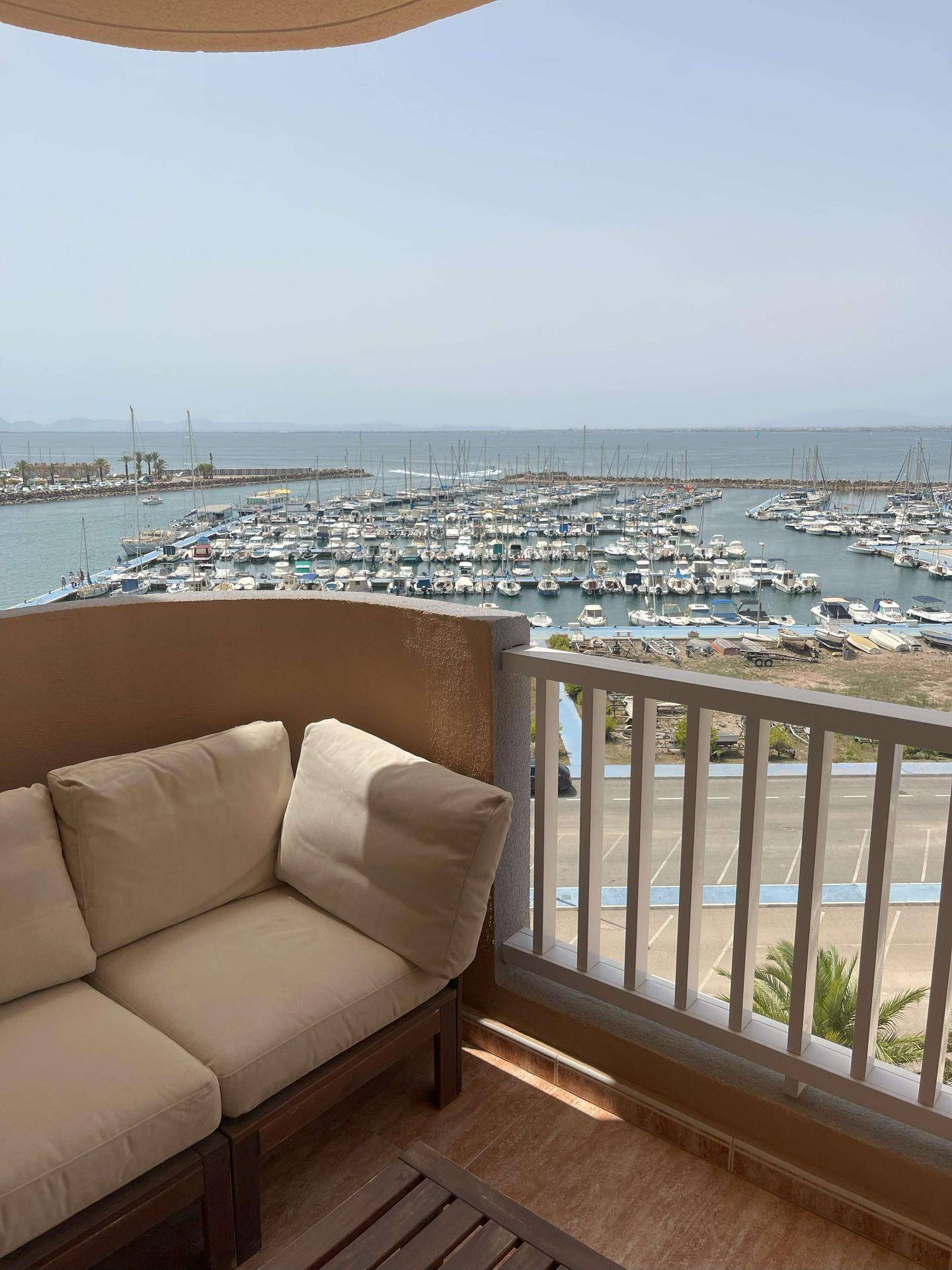 Gemütlicher Balkon mit Sitzgelegenheiten und weitem Blick auf den Yachthafen und das Meer.