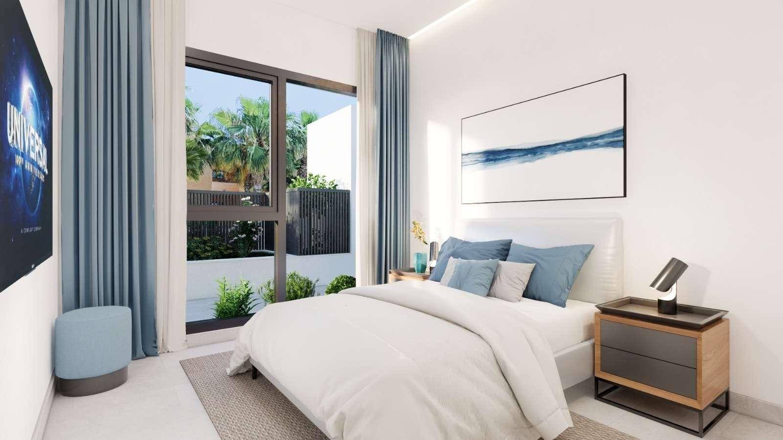 Modernes Schlafzimmer mit großem Fenster, Blick ins Grüne und einem an der Wand montierten Fernseher.