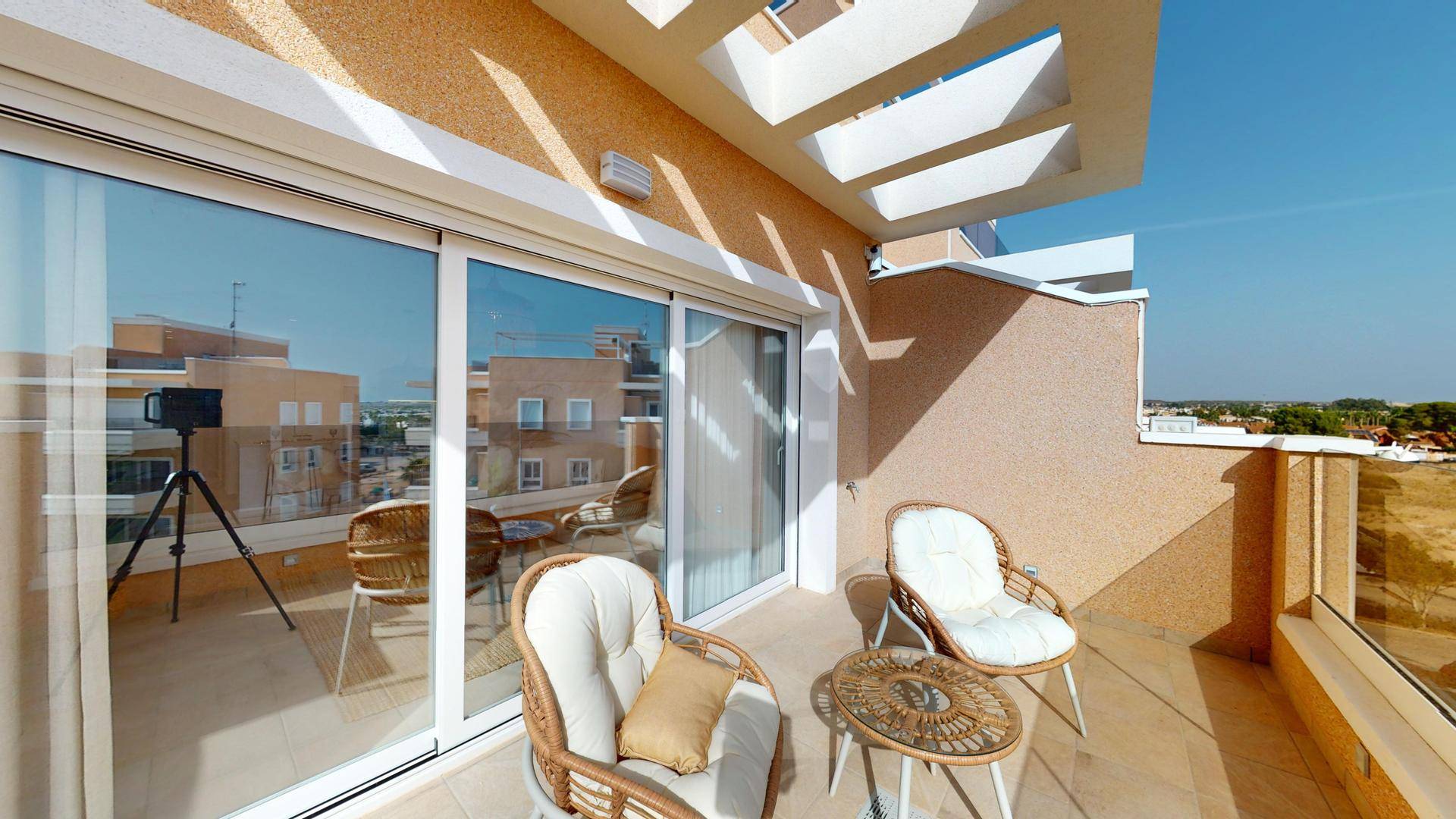 Sonniger Balkon mit bequemen Korbsesseln und Blick auf die umliegenden Gebäude.