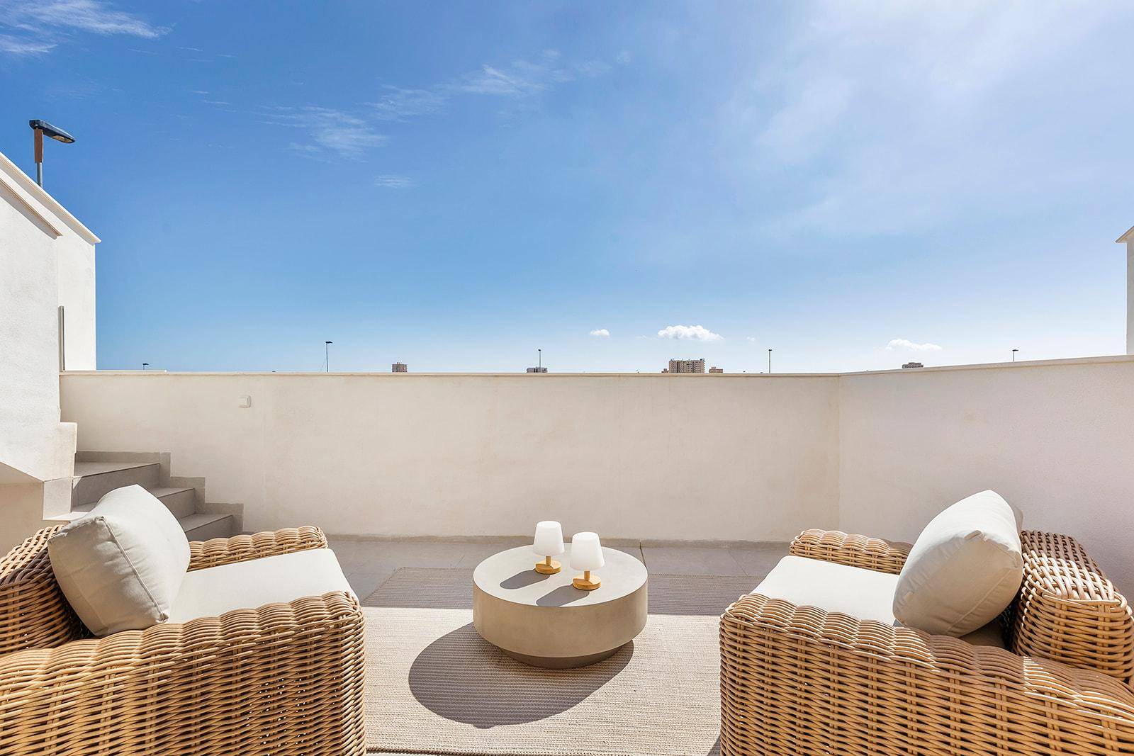 Sonnige Dachterrasse mit bequemen Sitzgelegenheiten und weitem Blick unter blauem Himmel.