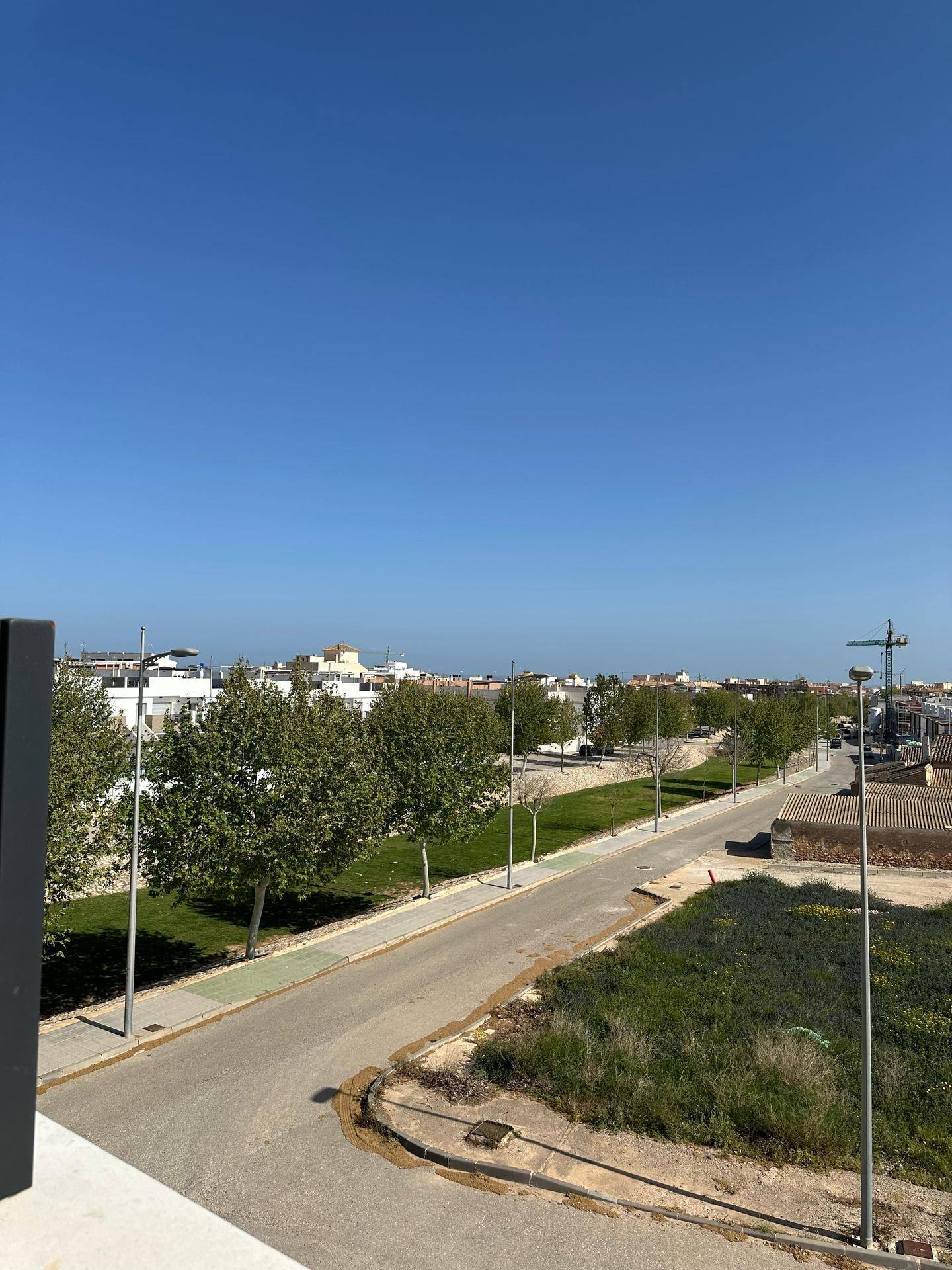 Weitblick über die Umgebung mit Straße, Bäumen und weiteren Gebäuden unter blauem Himmel.
