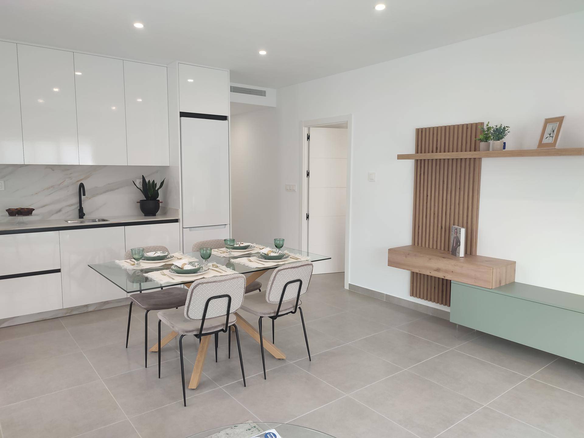 Essbereich mit modernem Glastisch, Stühlen und einer stilvollen Wanddekoration aus Holz.