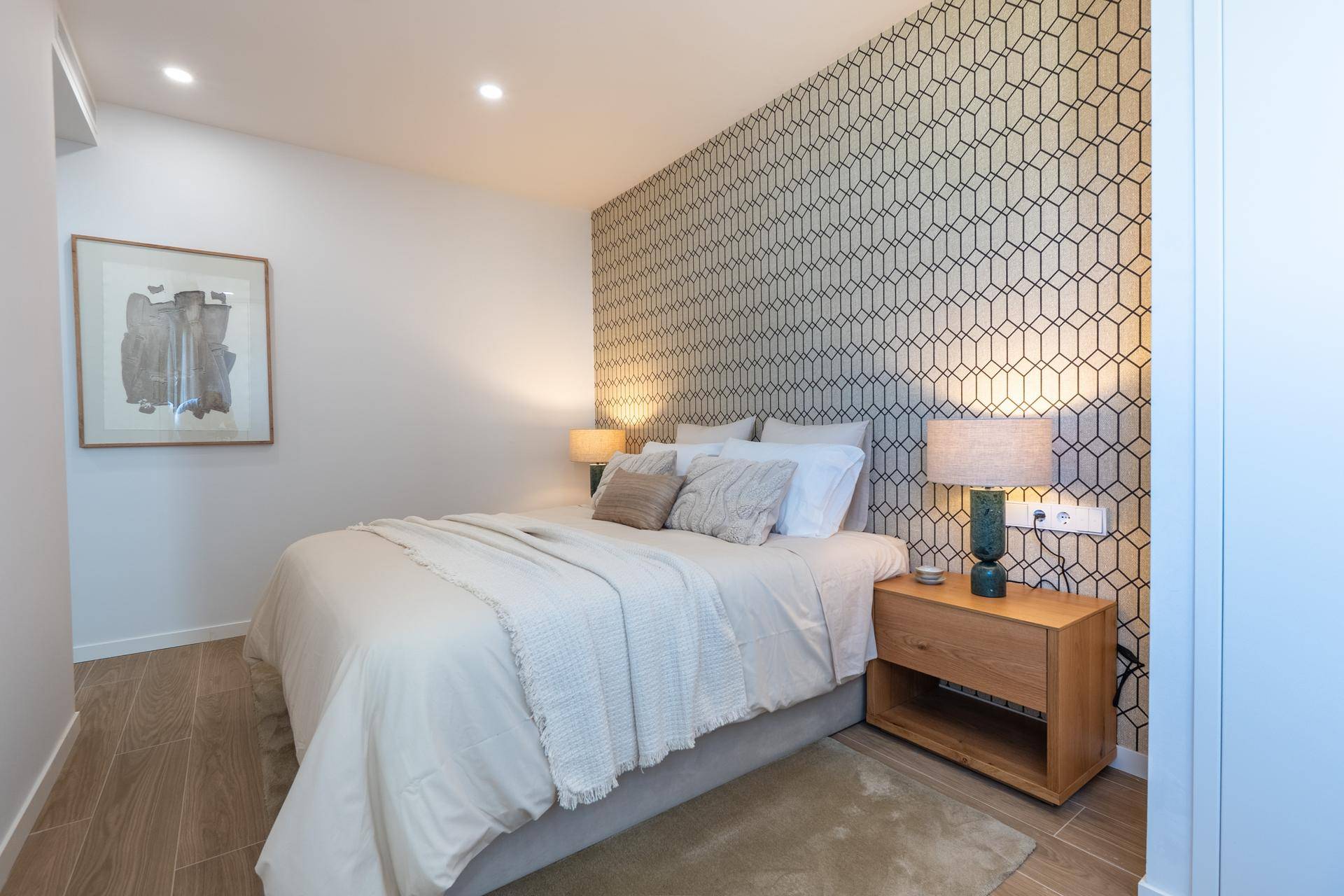 Helles Schlafzimmer mit Doppelbett, stilvoller Tapete und Holzboden, ideal zum Entspannen.
