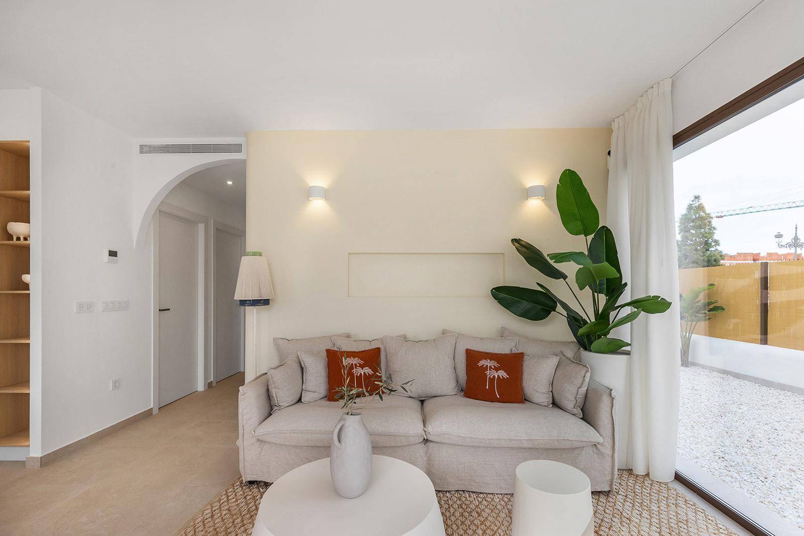 Helles Wohnzimmer mit beigem Sofa und Blick auf den Flur mit Torbogen.