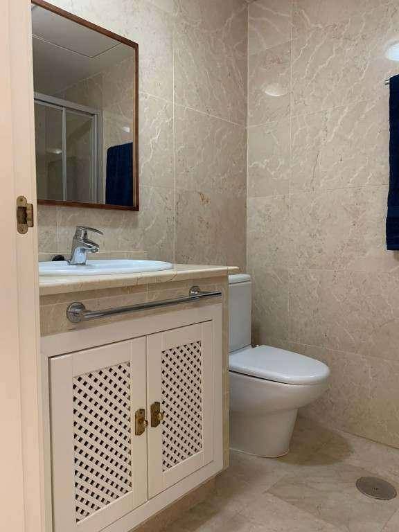 Modernes Badezimmer mit Waschbecken, Spiegel und Toilette, ausgestattet mit hellen Fliesen.