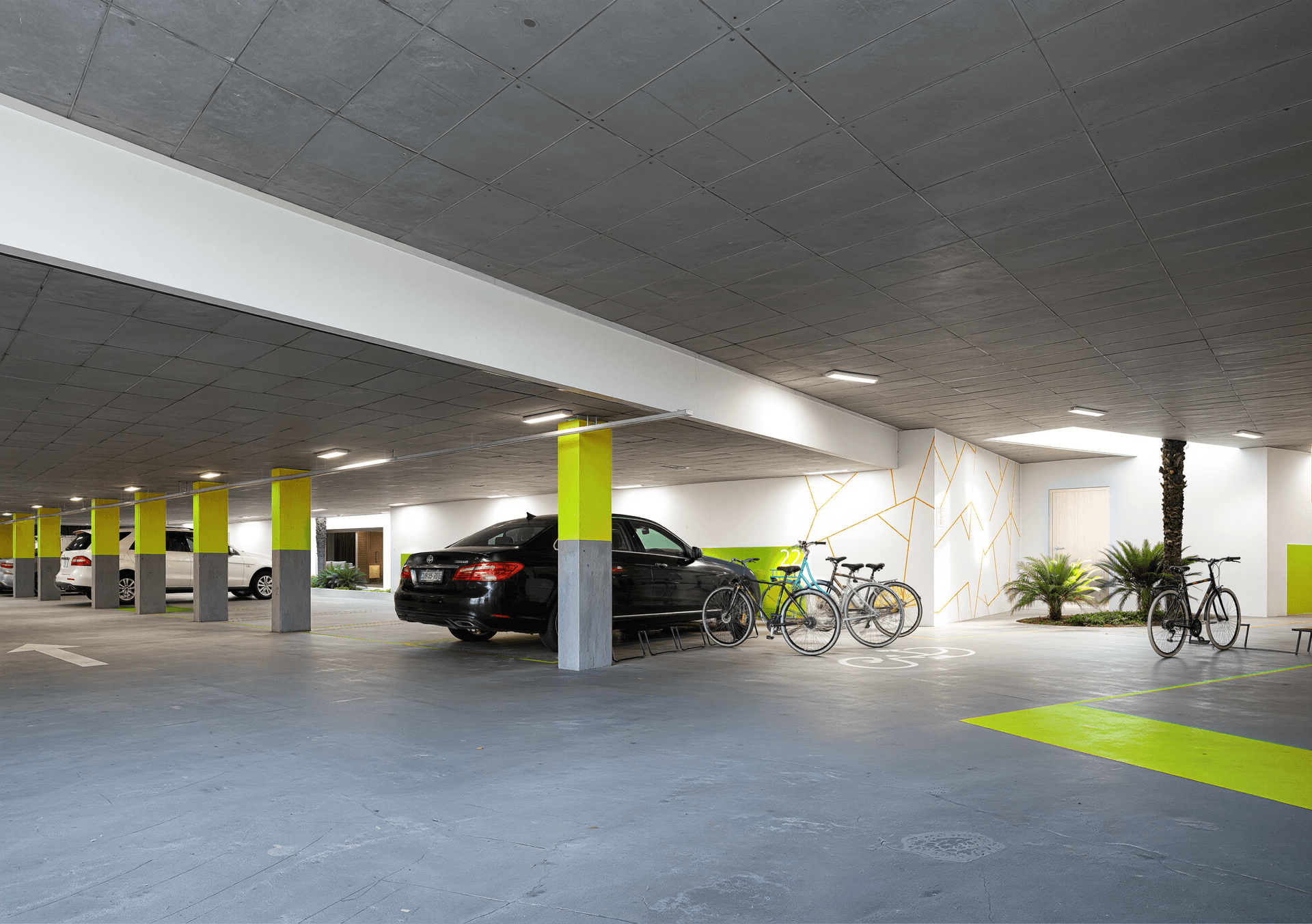 Tiefgarage mit Parkplätzen, Fahrradständern und dekorativen Elementen.