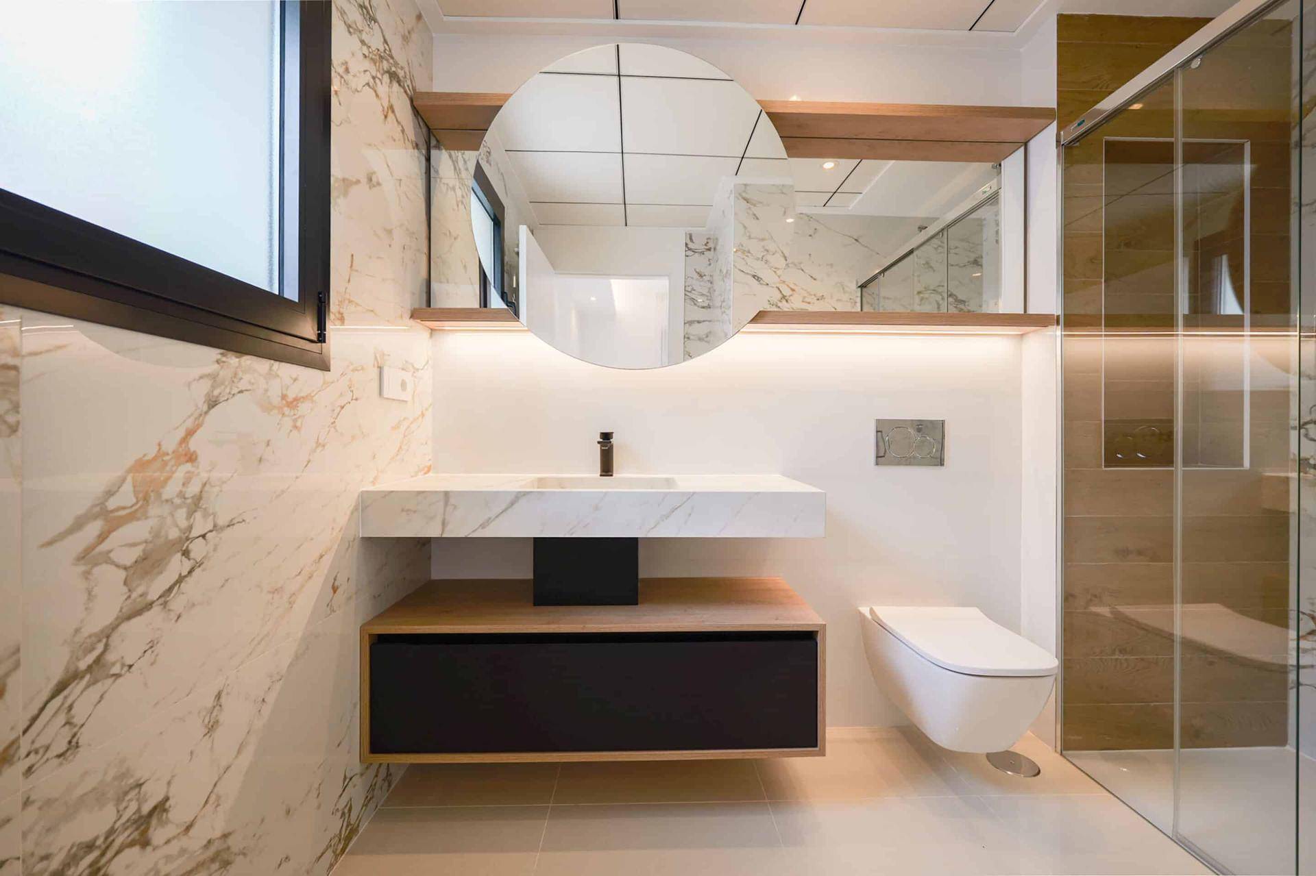 Elegantes Badezimmer mit schwebendem Waschtisch, runden Spiegeln und begehbarer Dusche.
