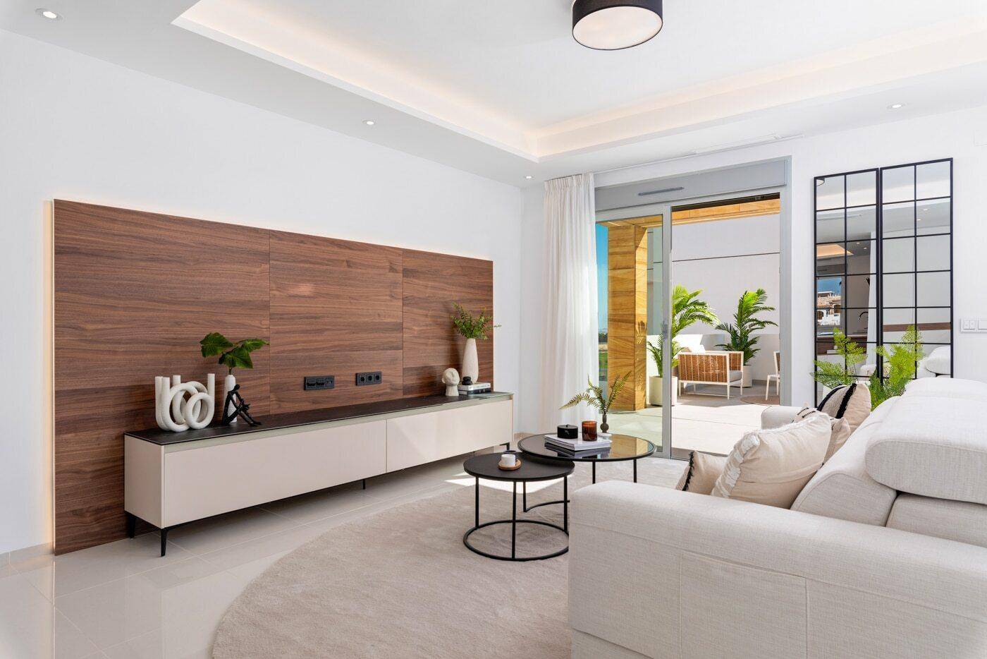 Helles Wohnzimmer mit moderner Einrichtung, Holzwandpaneel und Zugang zur Terrasse.