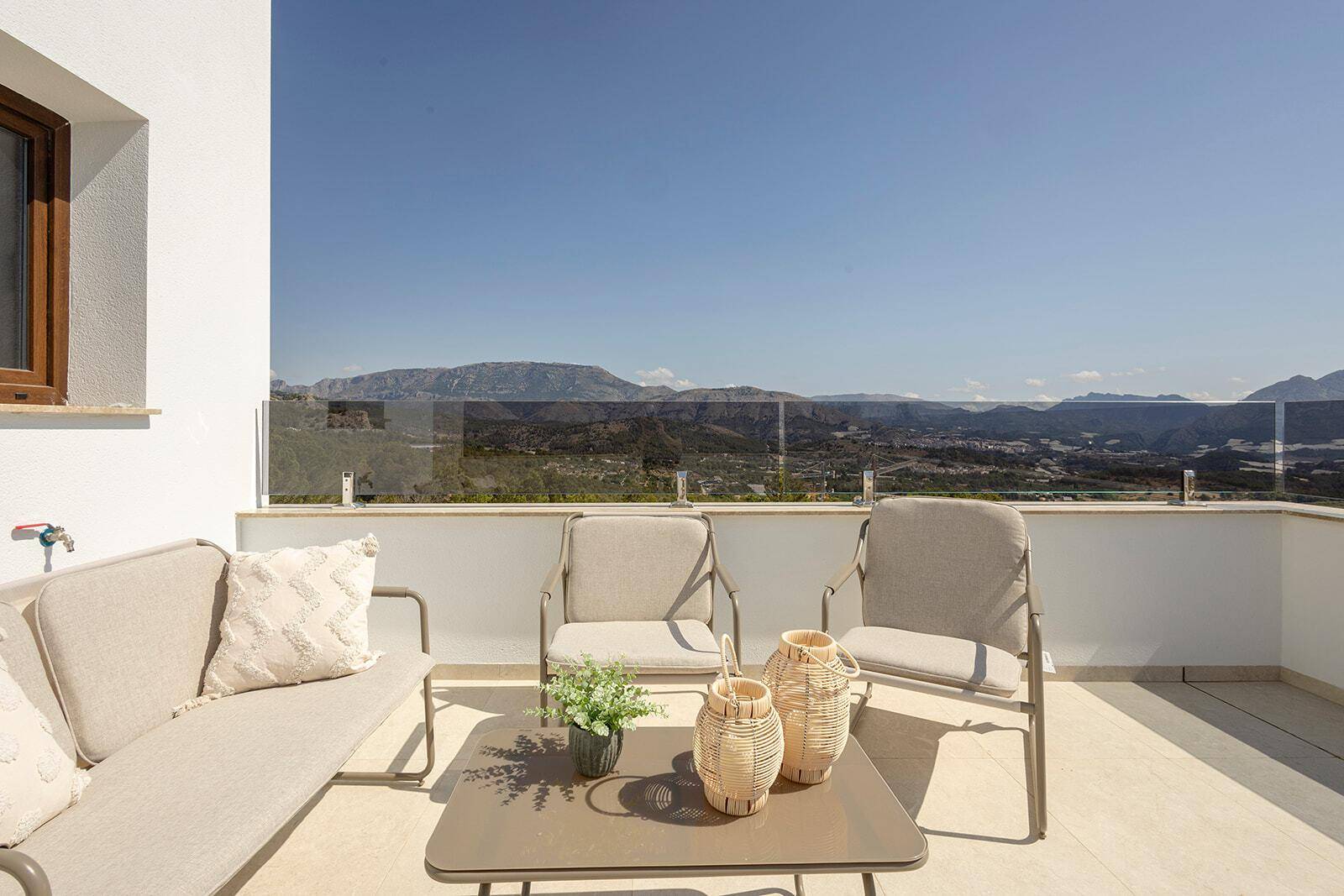 Sonnige Terrasse mit Sitzgelegenheiten und weitem Panoramablick auf Berge und Tal.
