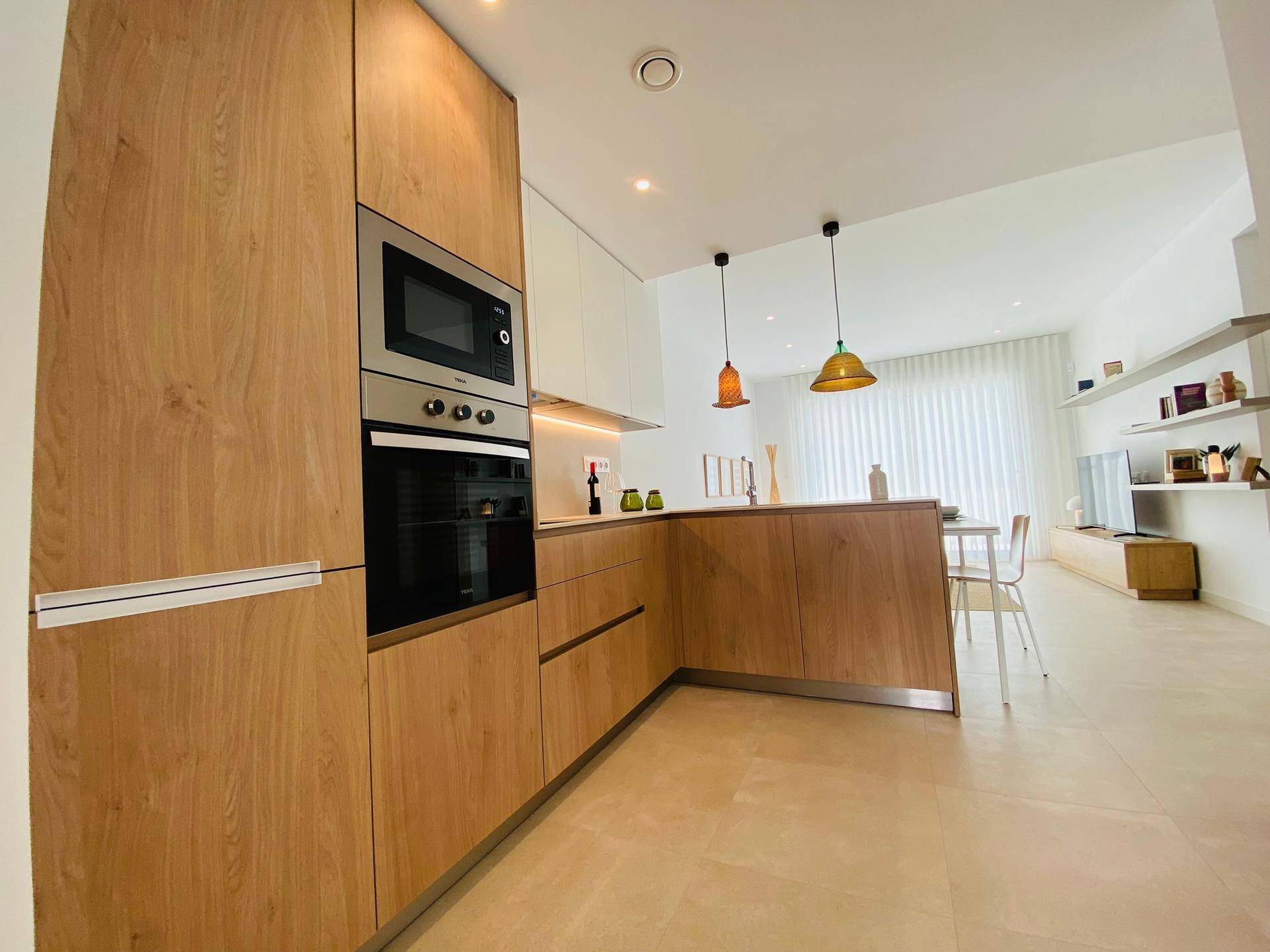Moderne Holzküche mit integrierten Geräten und offenem Übergang zum Wohnbereich.