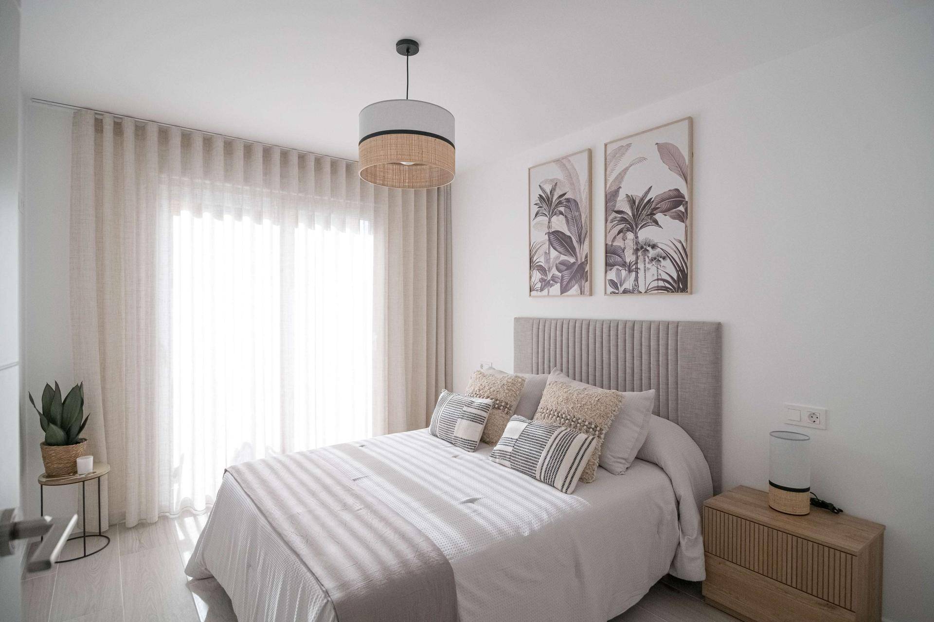 Helles Schlafzimmer mit Doppelbett, stilvoller Einrichtung und Zugang zum Balkon.