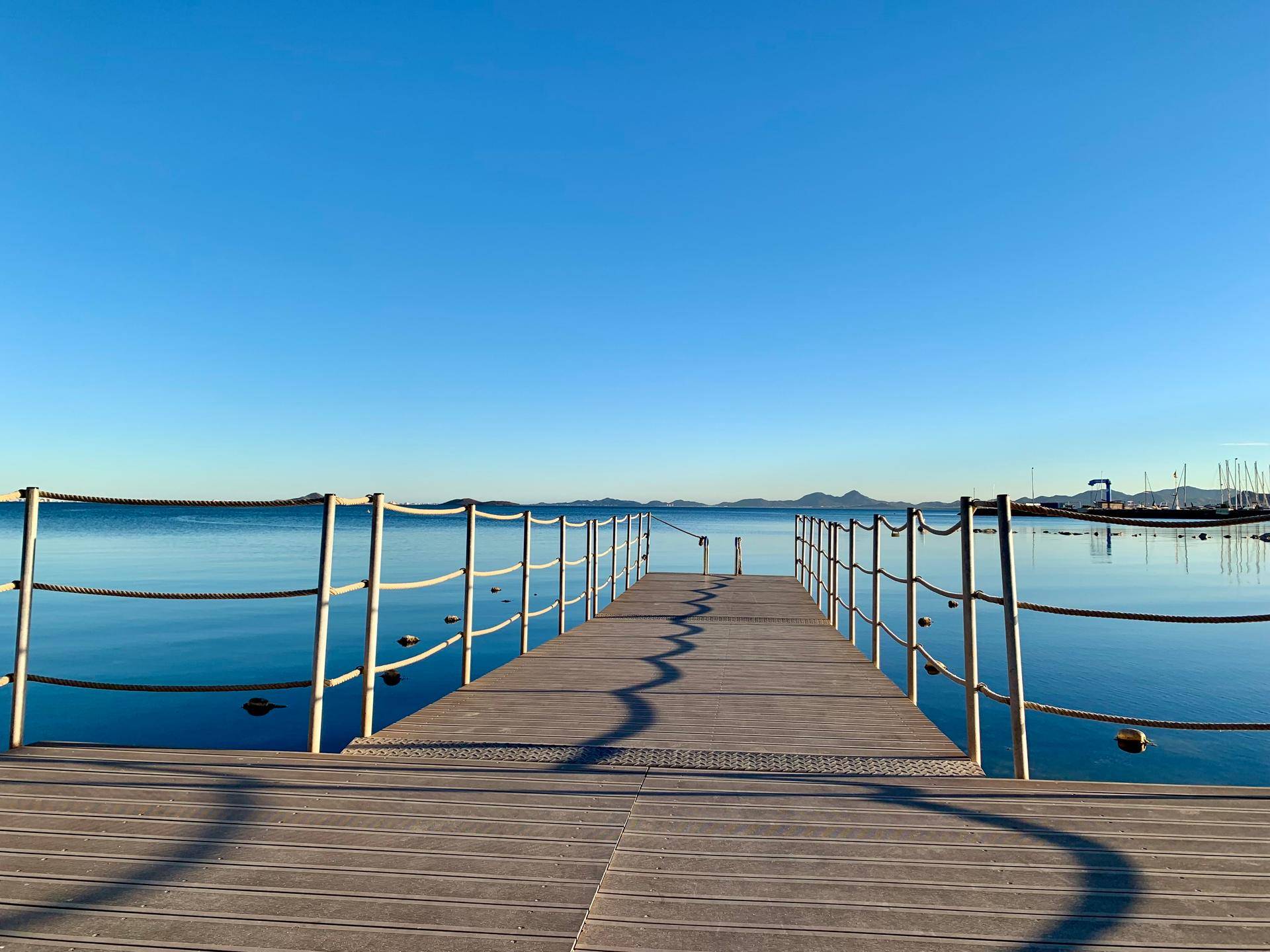 Holzsteg ragt in das ruhige, blaue Meer, umgeben von einer weiten Wasserlandschaft.
