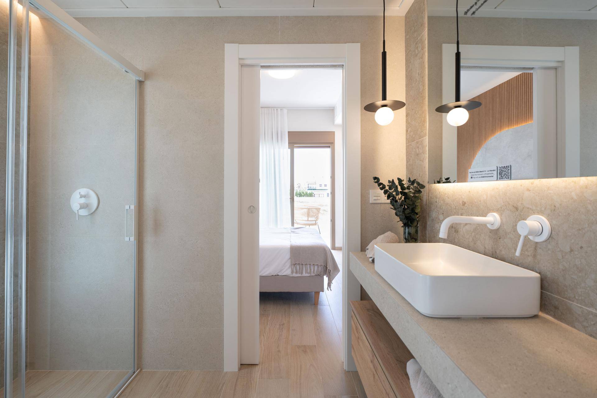 Modernes Badezimmer mit begehbarer Dusche, Einzelwaschbecken und Zugang zum Schlafzimmer.