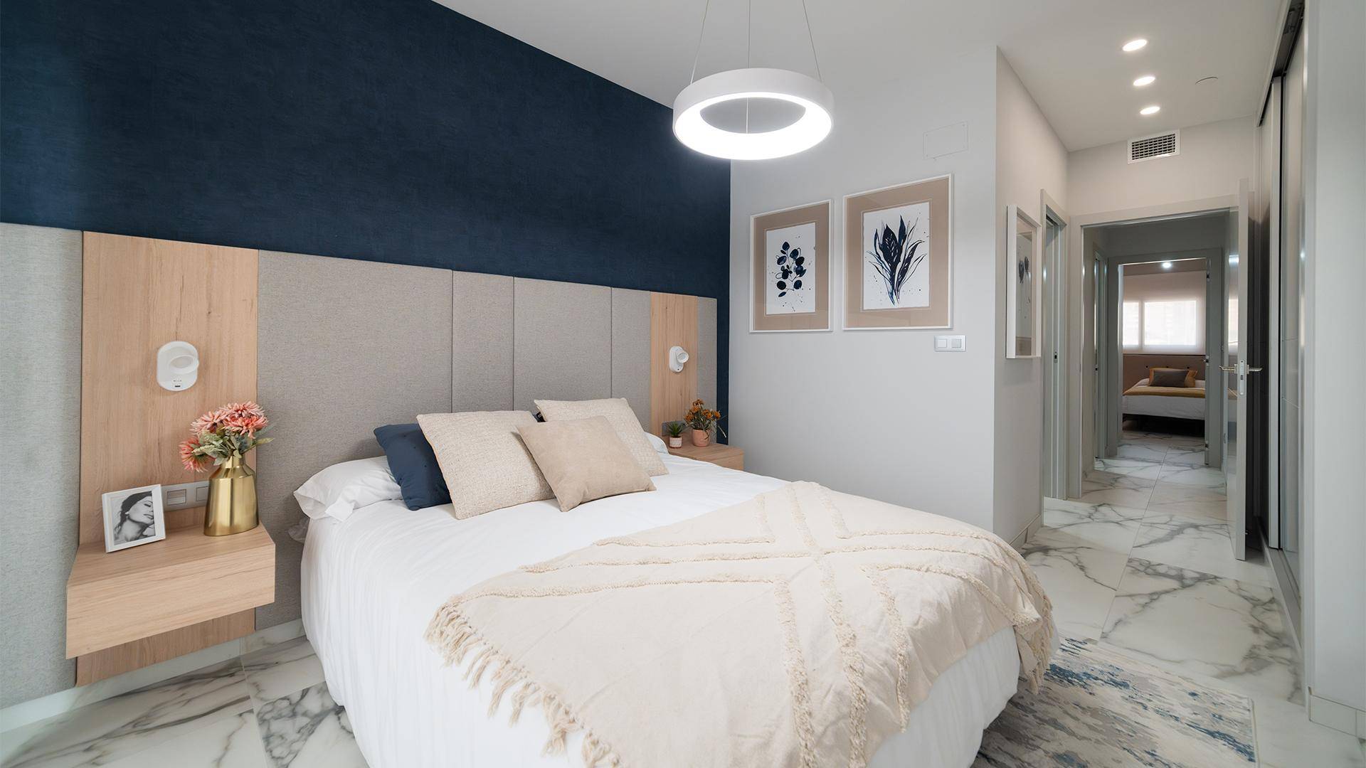 Modernes Schlafzimmer mit Doppelbett, blauer Akzentwand und Marmorboden.