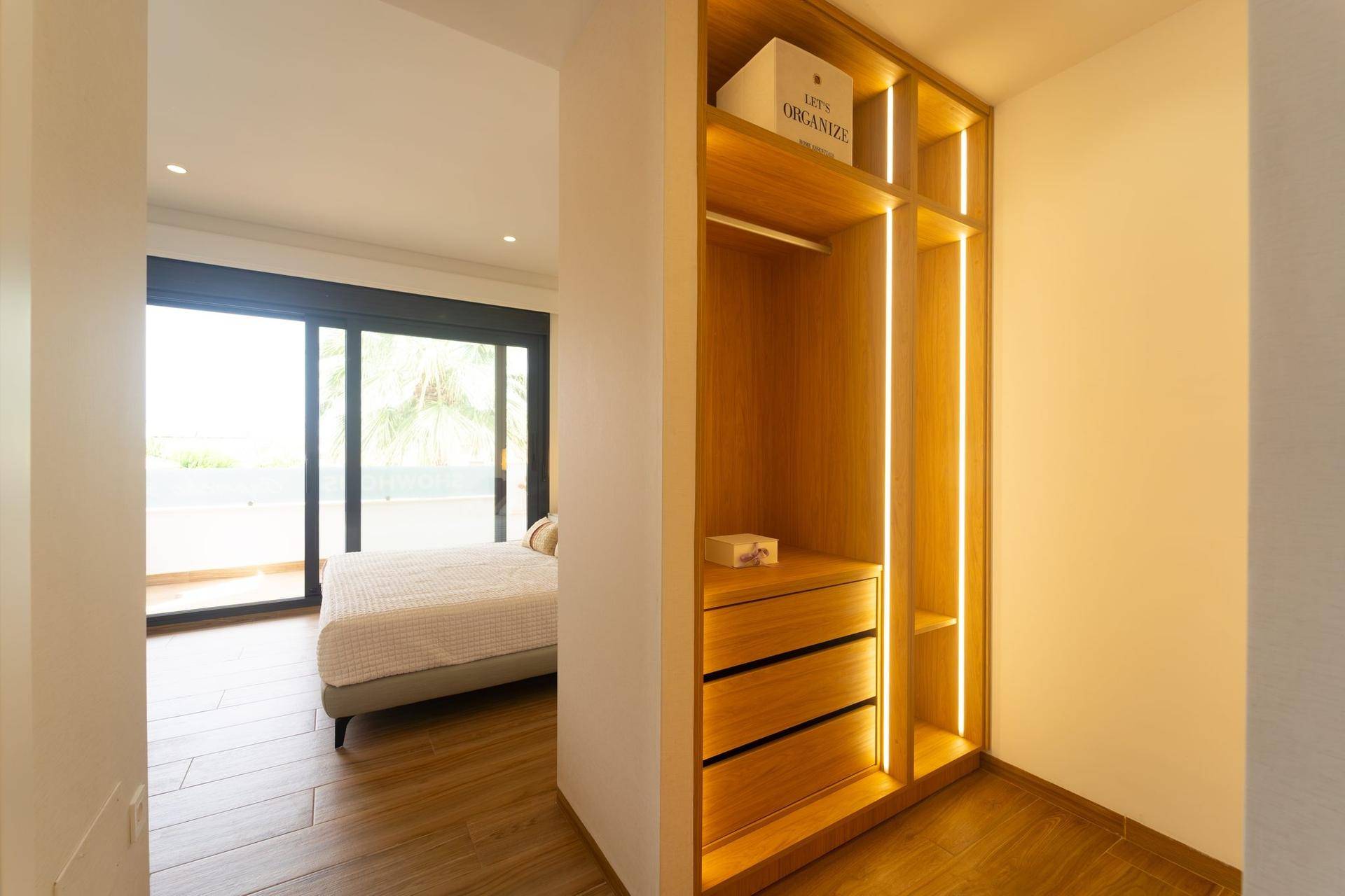 Heller begehbarer Kleiderschrank mit Holzregalen und direktem Zugang zum Schlafzimmer.