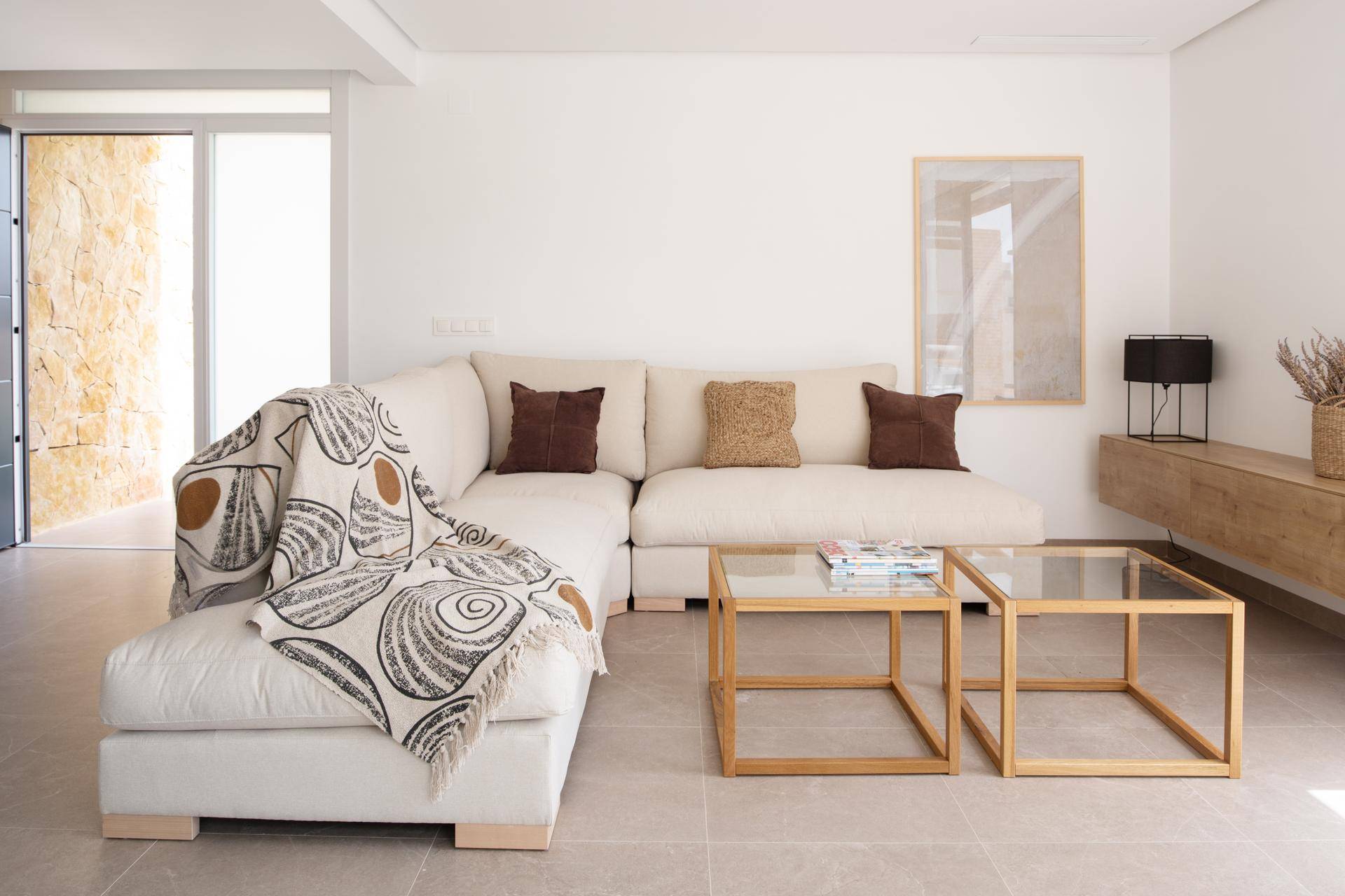 Gemütliches Wohnzimmer mit großem Ecksofa, modernen Couchtischen und Blick auf die Natursteinwand.