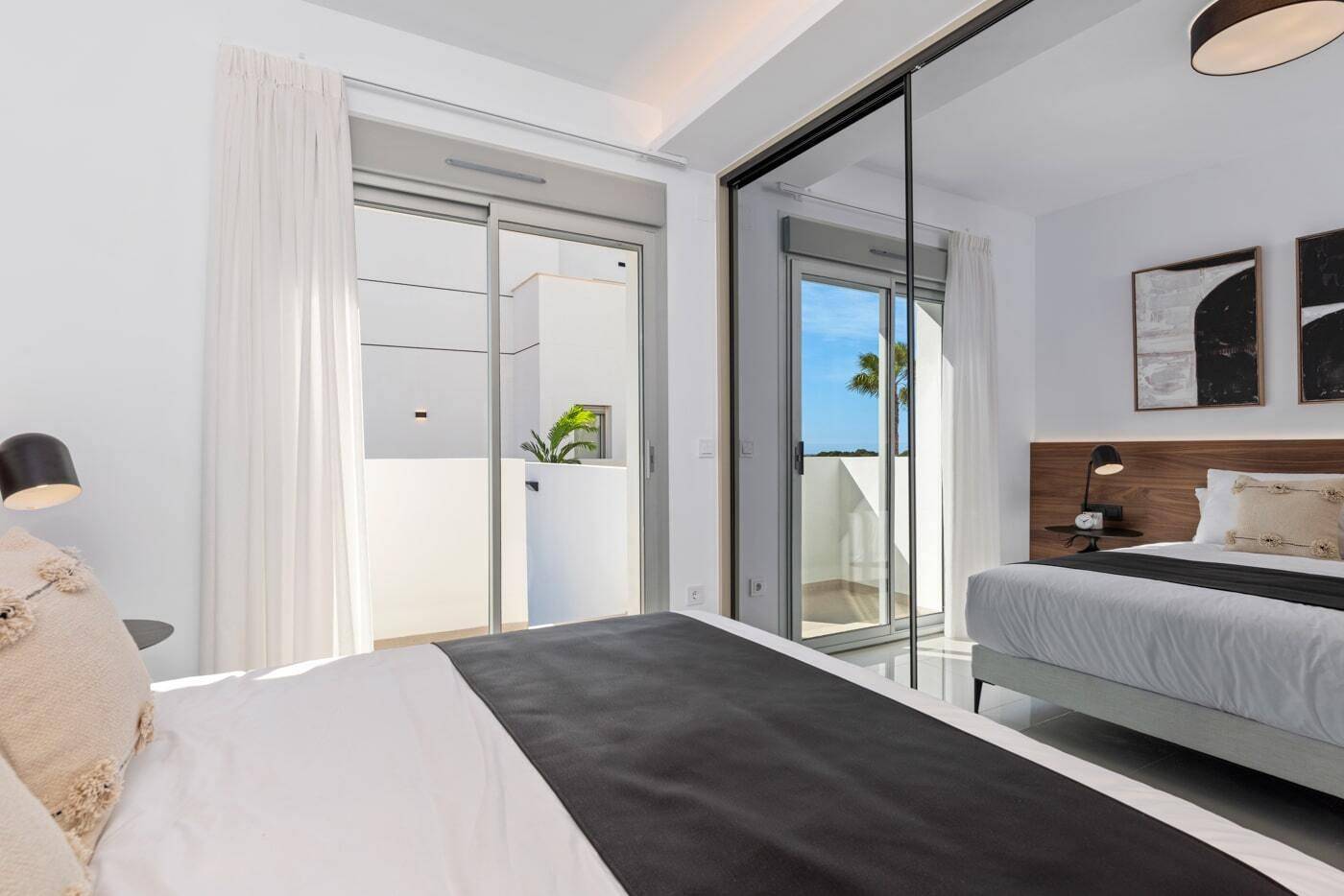 Modernes Schlafzimmer mit Schiebetüren zum Balkon und integrierten Spiegelschränken.