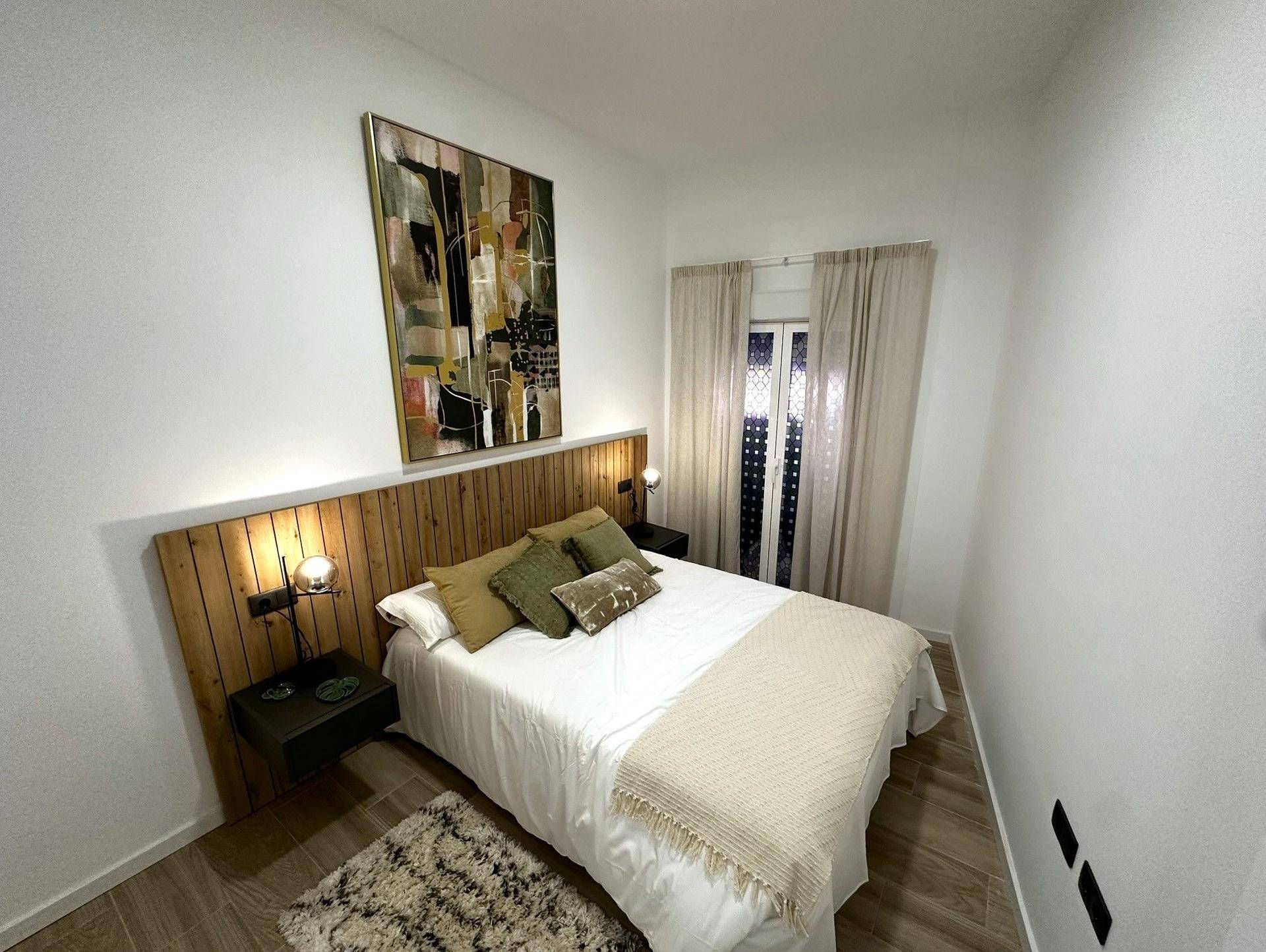 Ruhiges Schlafzimmer mit Doppelbett, Holzkopfteil und einem Fenster für natürliches Licht.