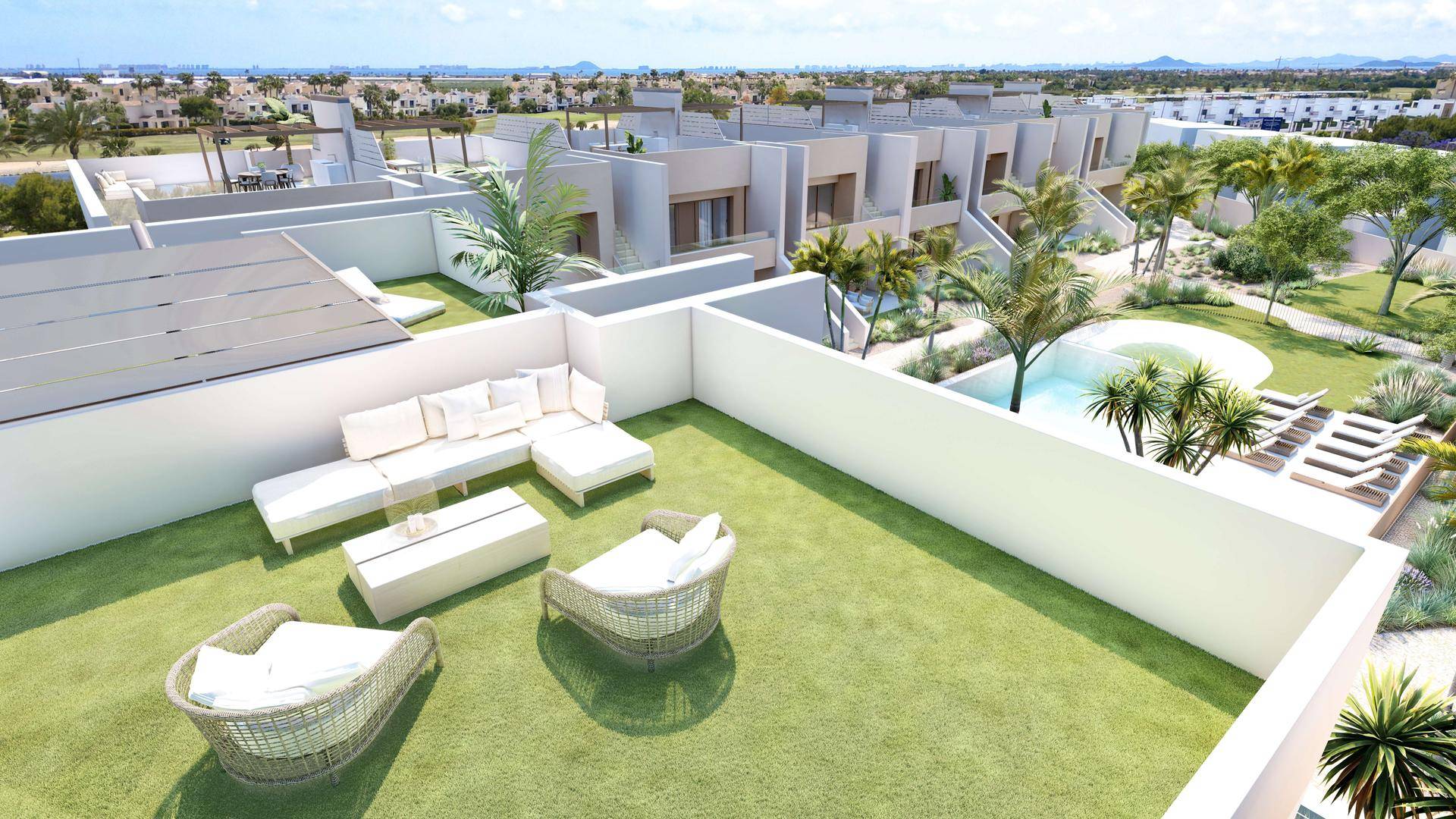 Grüne Dachterrasse mit bequemen Lounge-Möbeln und Blick auf die Wohnanlage und den Pool.