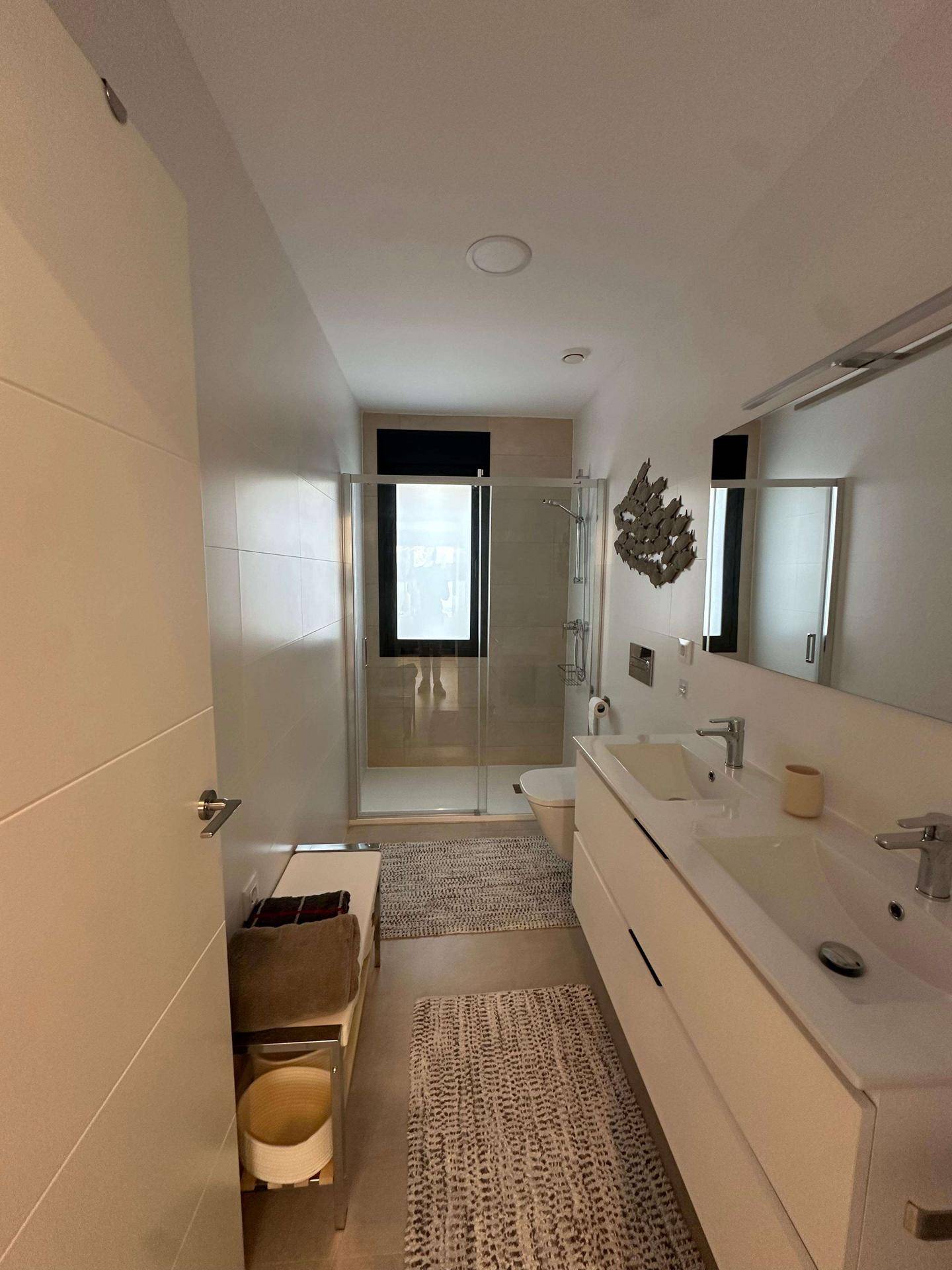 Modernes Badezimmer mit Doppelwaschbecken, großer Dusche und Fenster für Tageslicht.