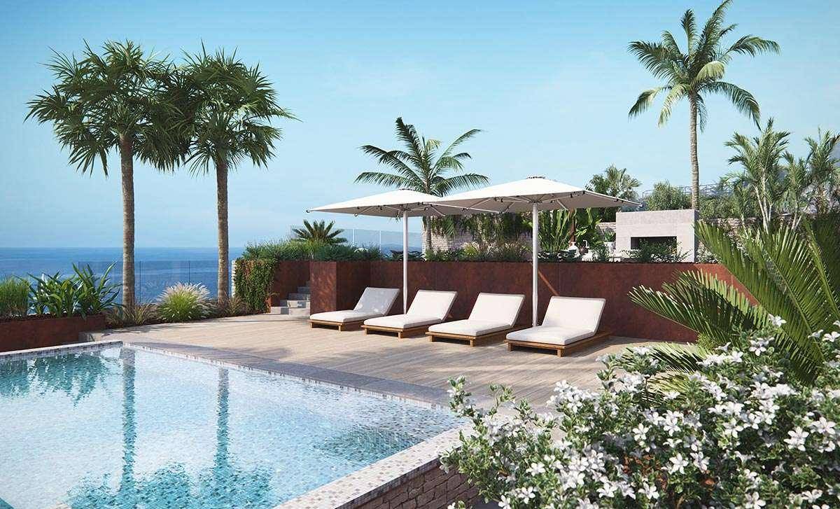 Großzügiger Poolbereich mit vielen Sonnenliegen, großen Sonnenschirmen und Blick auf das Meer.