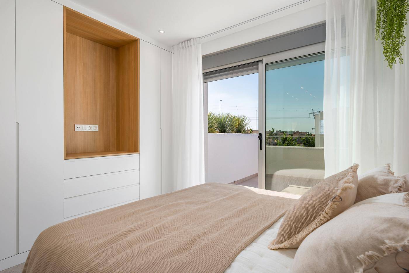 Schlafzimmer mit Schiebetür zum Balkon und integriertem Kleiderschrank, hell und luftig.