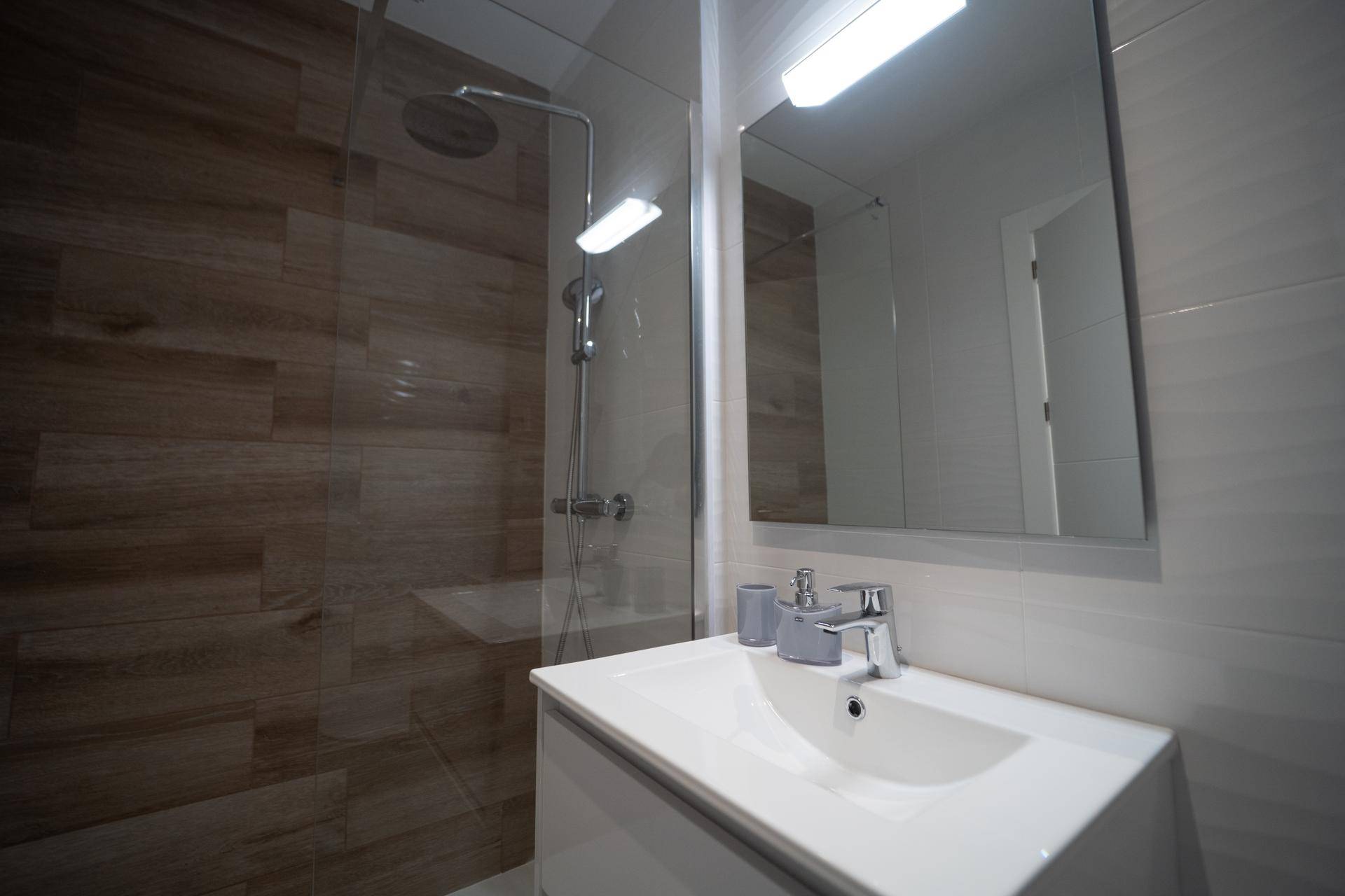 Modernes Badezimmer mit begehbarer Dusche, Einzelwaschbecken und Holzfliesen.
