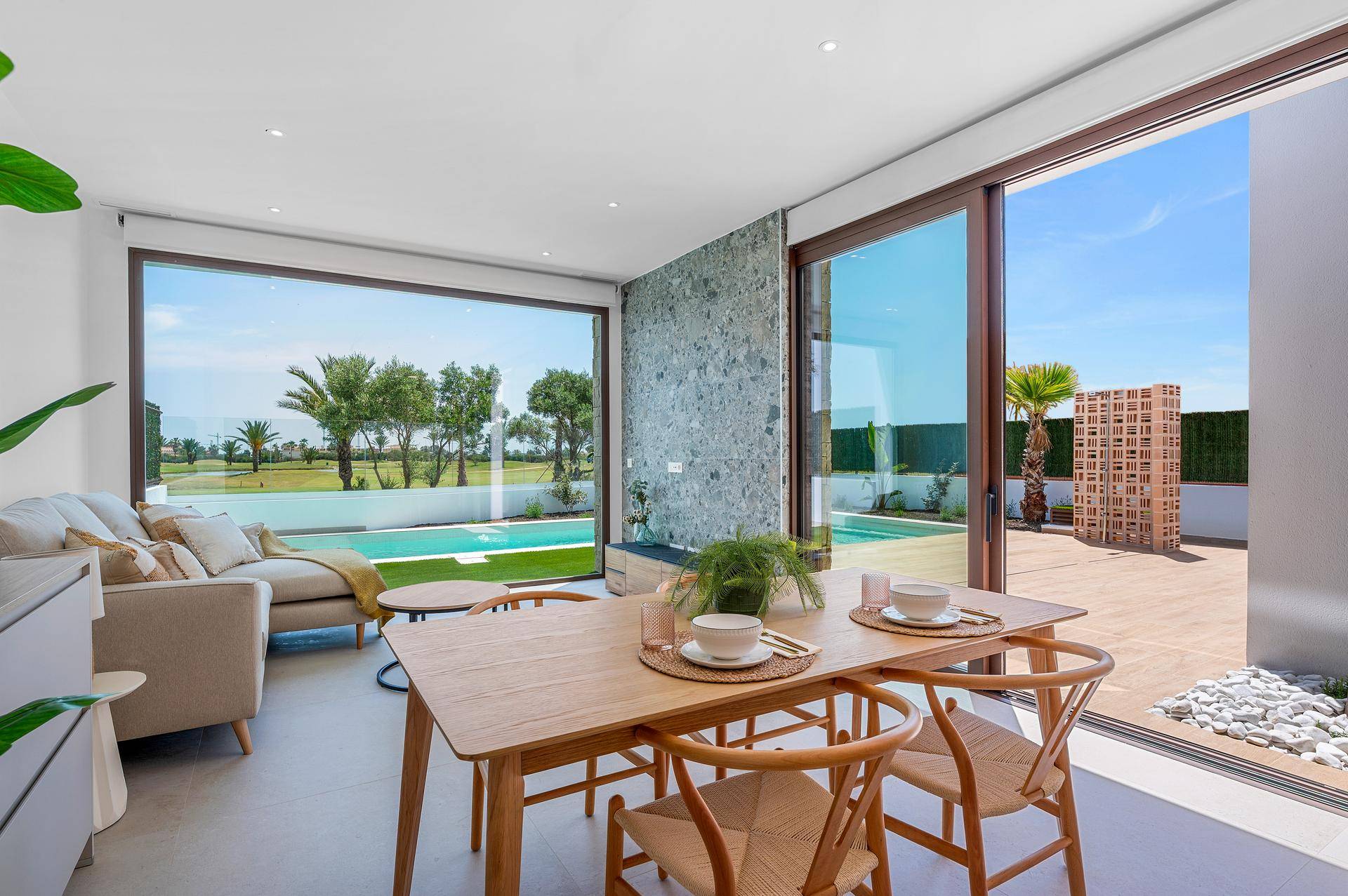 Heller Wohn- und Essbereich mit großen Fenstern, die den Blick auf den Pool und die Landschaft freigeben.