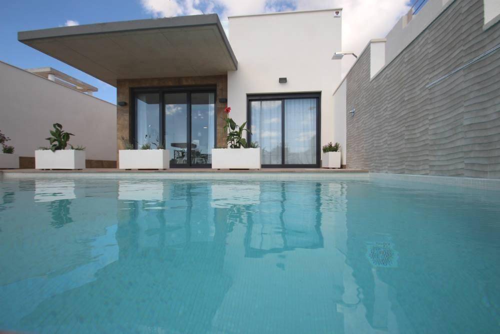 Nahaufnahme des privaten Pools vor der modernen Hausfassade mit großen Glasfronten.