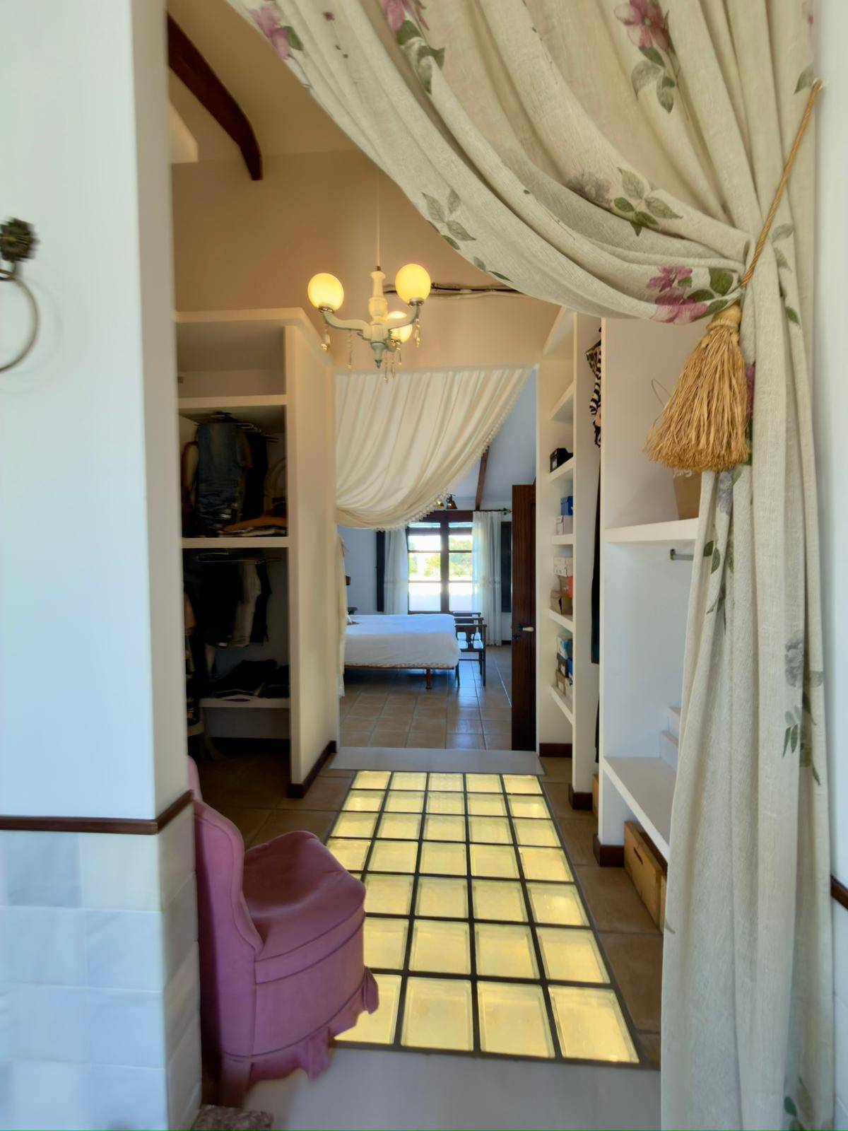 Begehbarer Kleiderschrank mit praktischen Regalen und Blick zum angrenzenden Schlafzimmer.