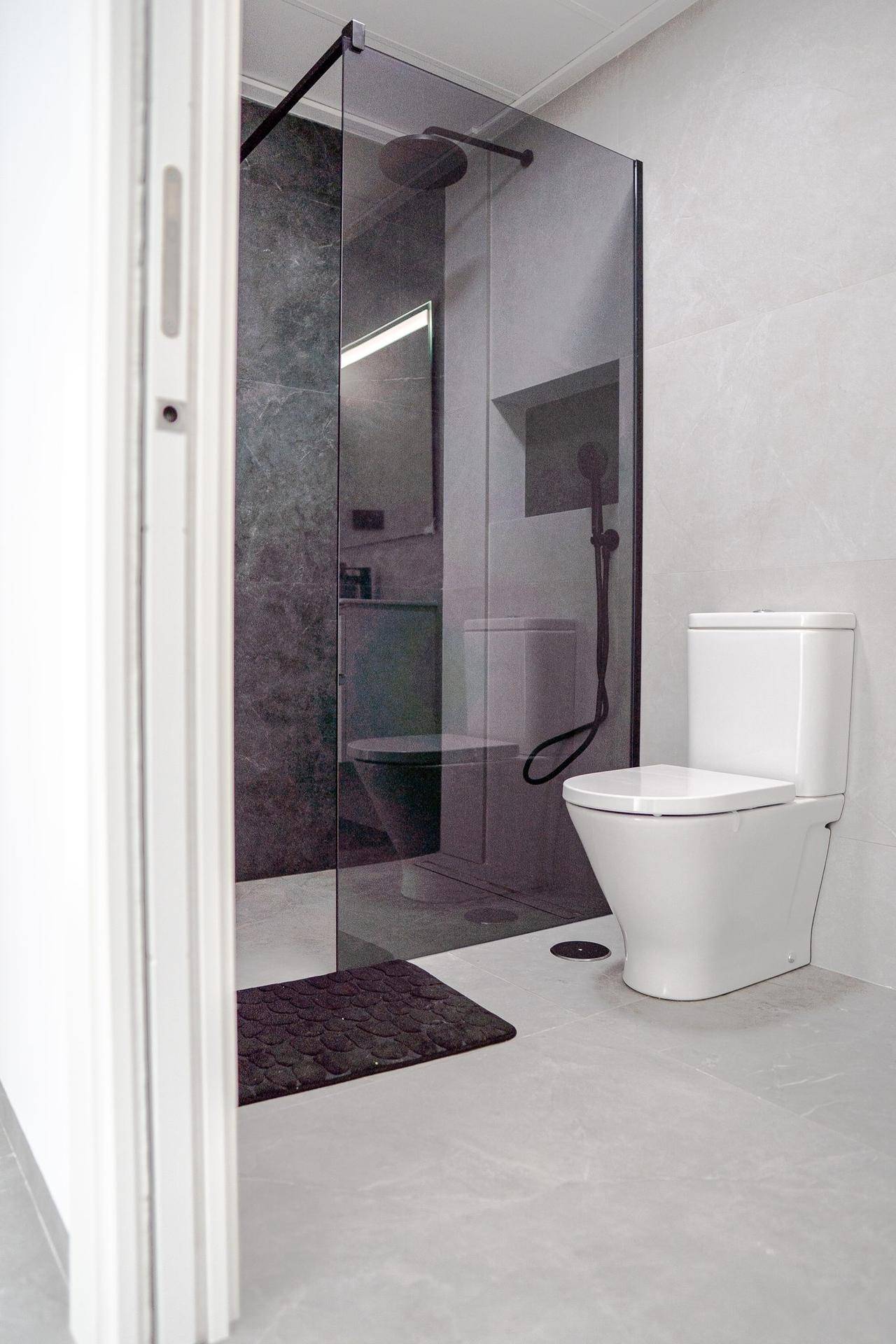 Modernes Badezimmer mit WC und begehbarer Dusche mit Glasabtrennung.