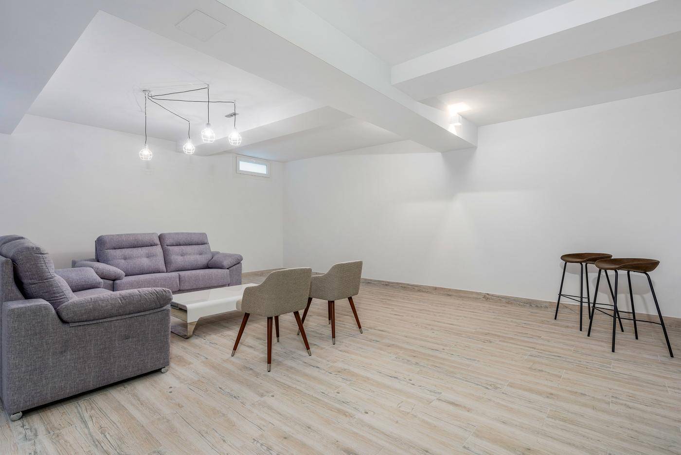 Geräumiger Kellerraum, eingerichtet als Wohnbereich mit Sofas und moderner Beleuchtung.
