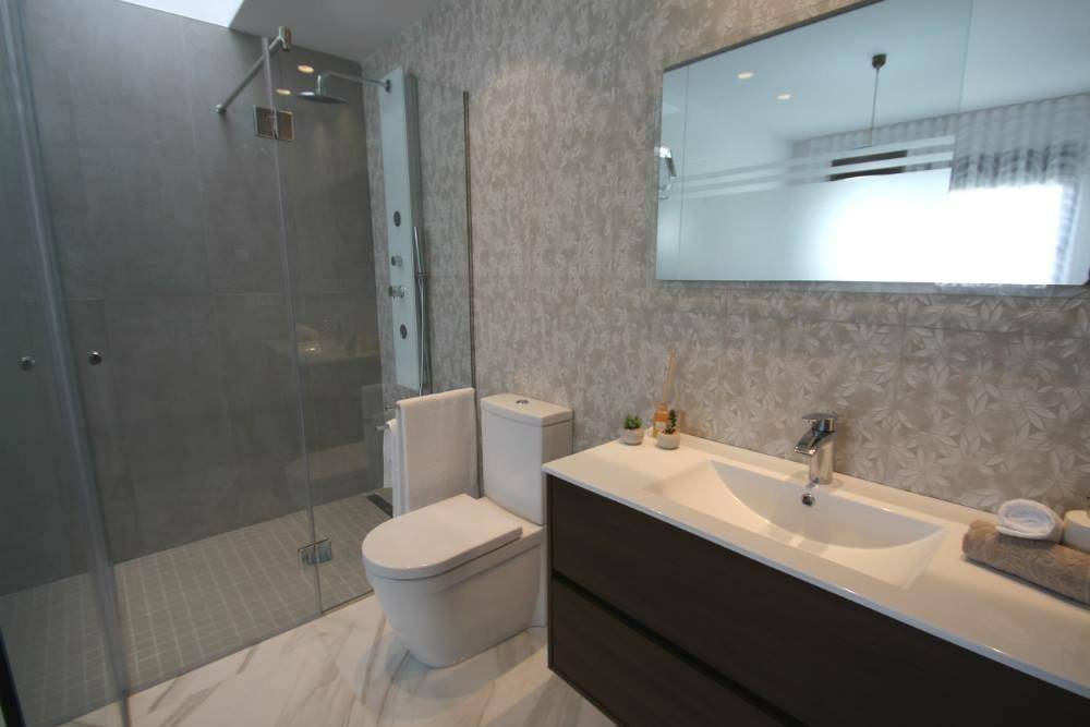Modernes Badezimmer mit großer Dusche, Waschtisch und floraler Tapete.