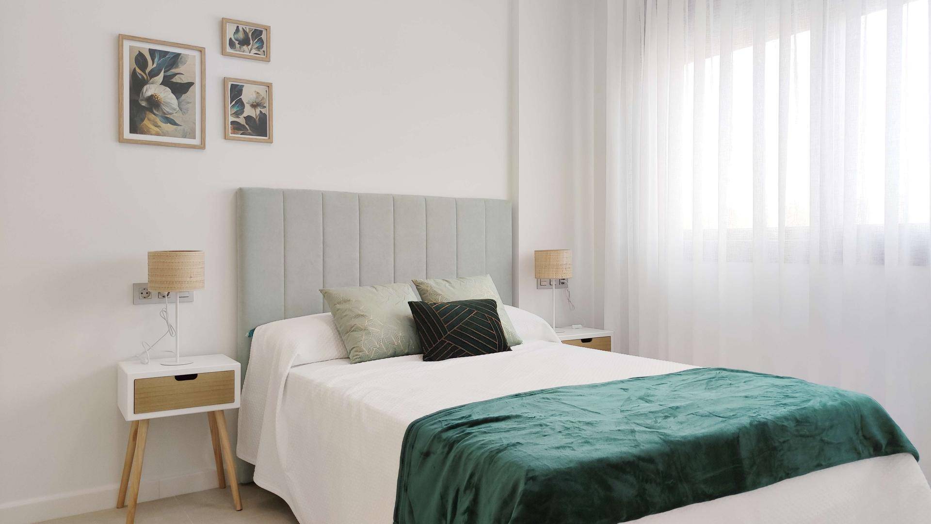 Helles Schlafzimmer mit Doppelbett, Nachttischen und großem Fenster.