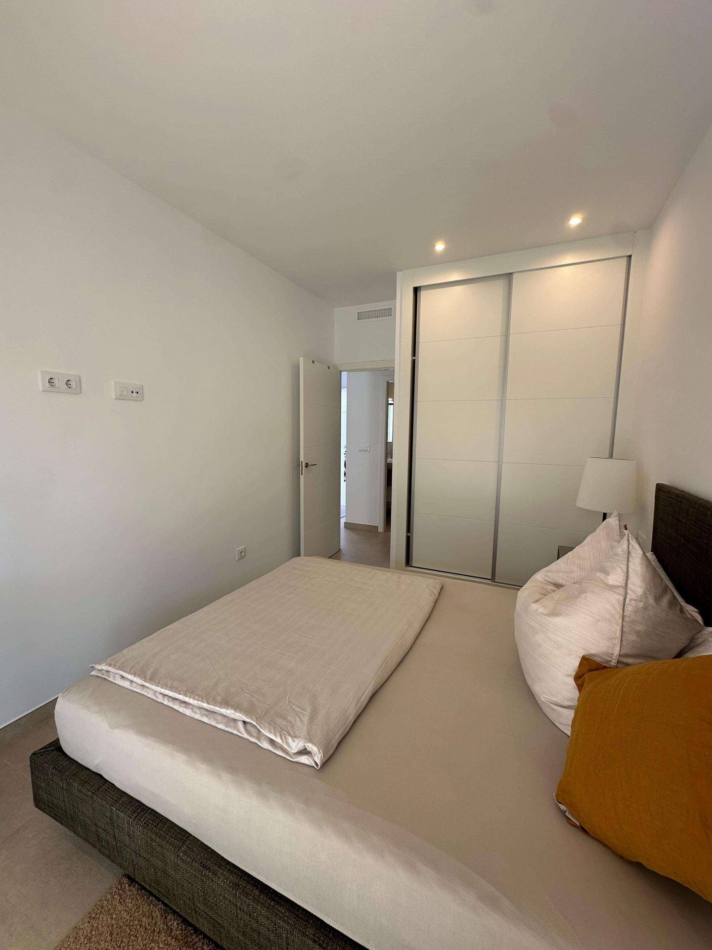 Schlafzimmer mit Doppelbett und integriertem Schiebetürenschrank.