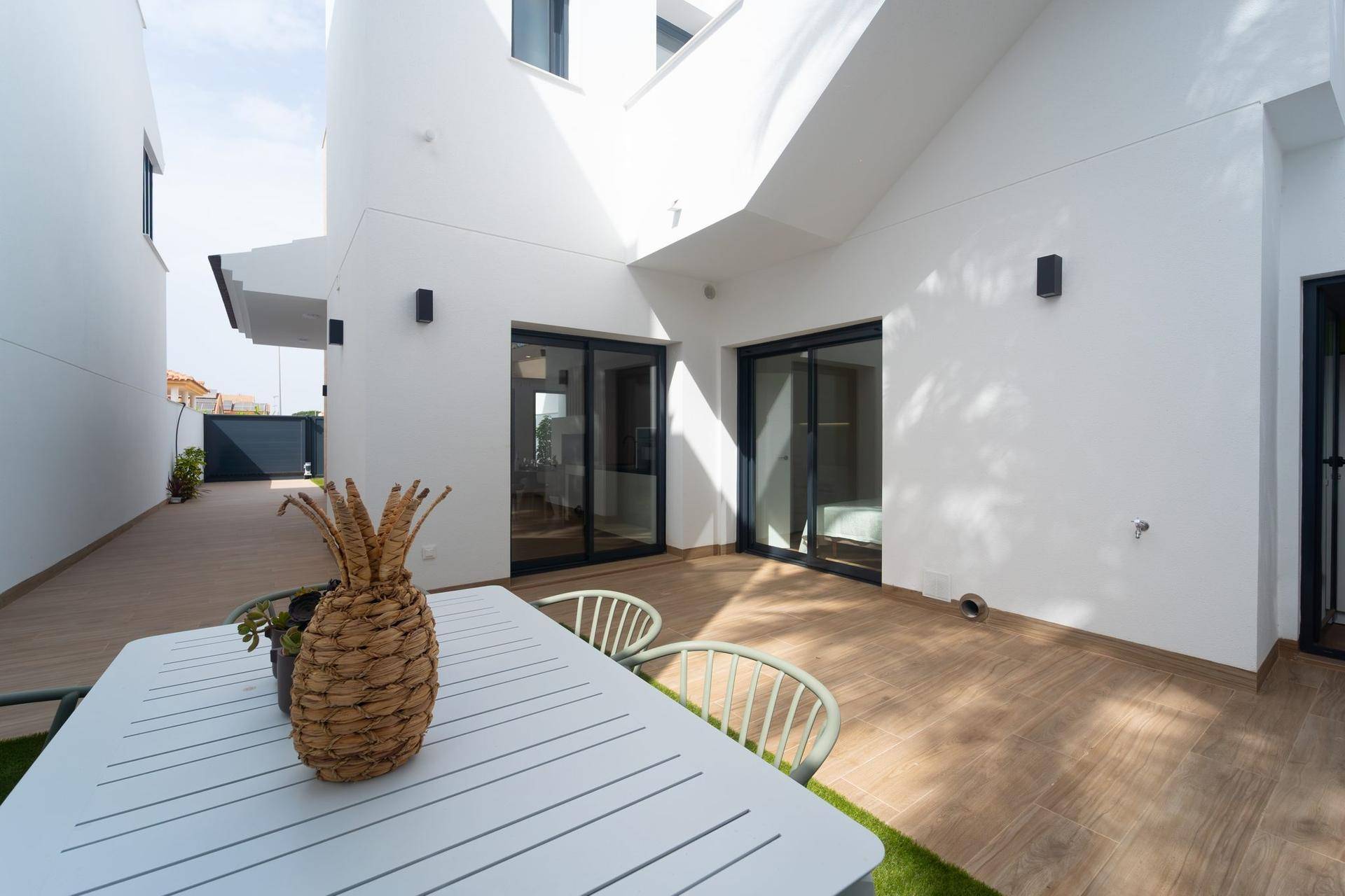 Geräumige Terrasse mit Esstisch und Blick auf den modernen Außenbereich des Hauses.