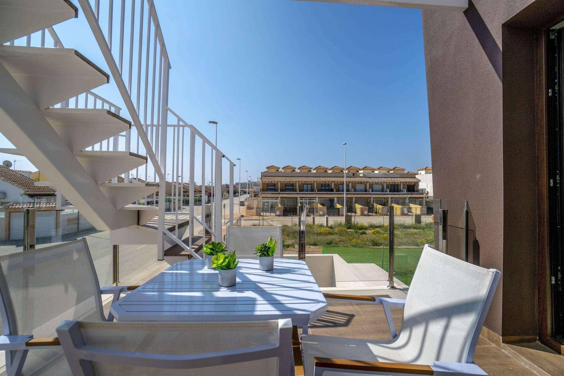 Heller Balkon mit Sitzgelegenheiten und Blick auf die Umgebung, verbunden durch eine Wendeltreppe.