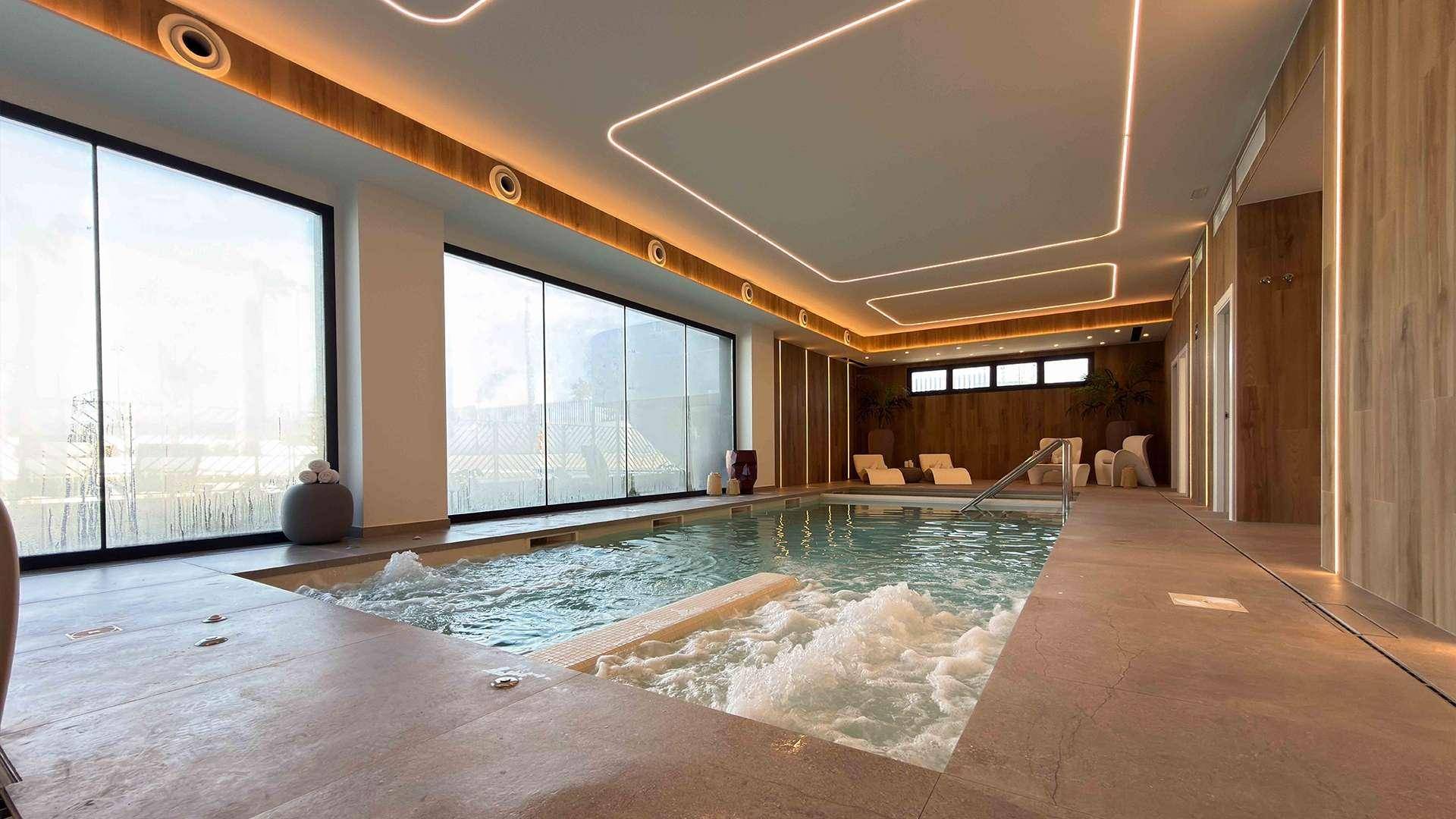 Moderner Innenpool mit Whirlpool-Funktion und stilvoller Beleuchtung in einem Wellnessbereich.