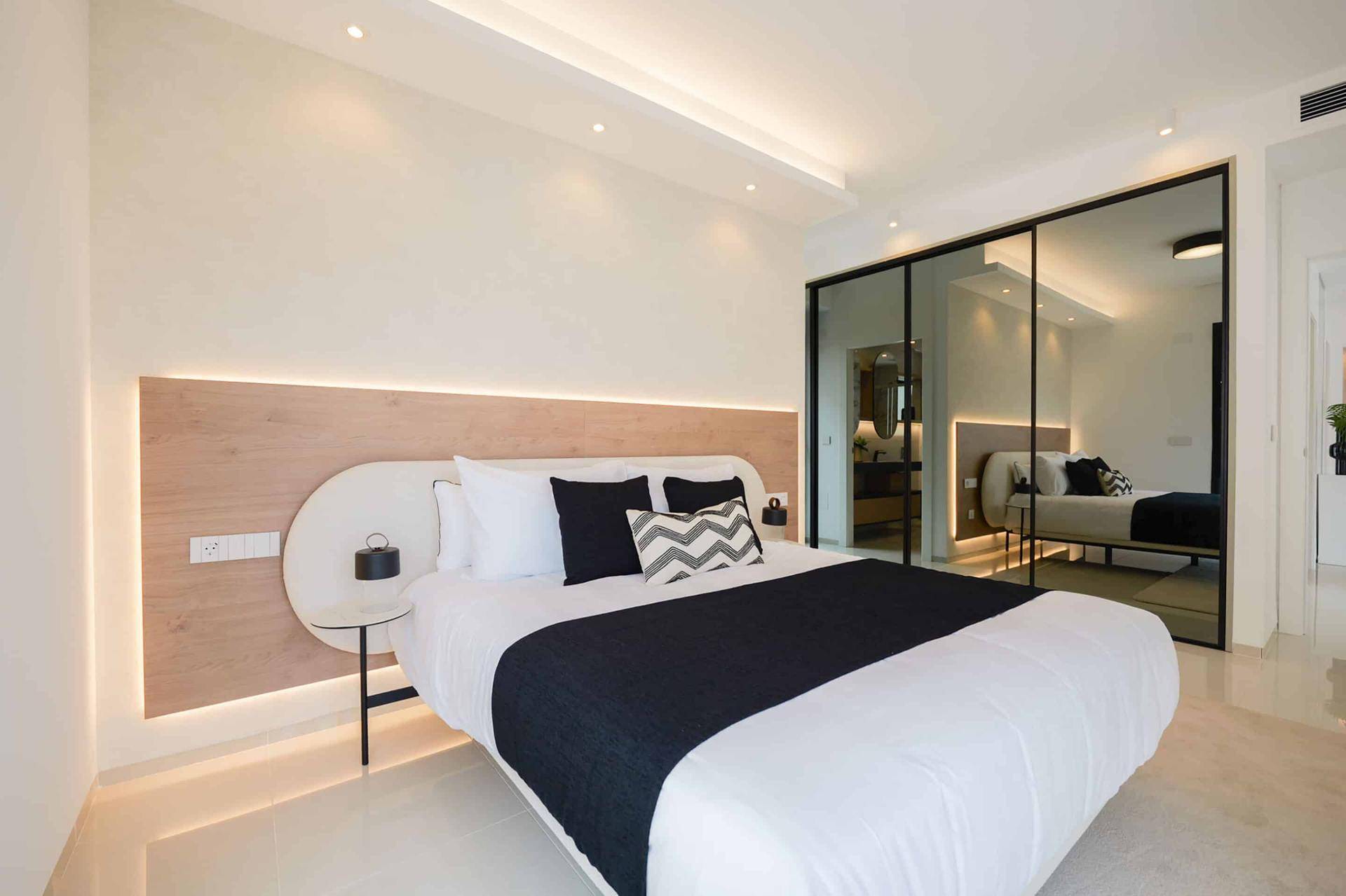 Schlafzimmer mit modernem Design, indirekter Beleuchtung und Spiegelwand.