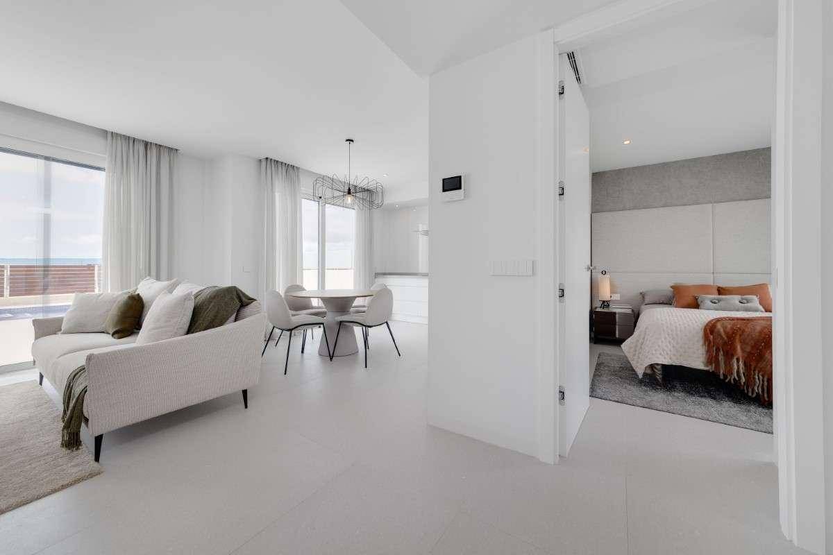 Offener Wohn- und Essbereich mit moderner Einrichtung und Blick auf ein angrenzendes Schlafzimmer.